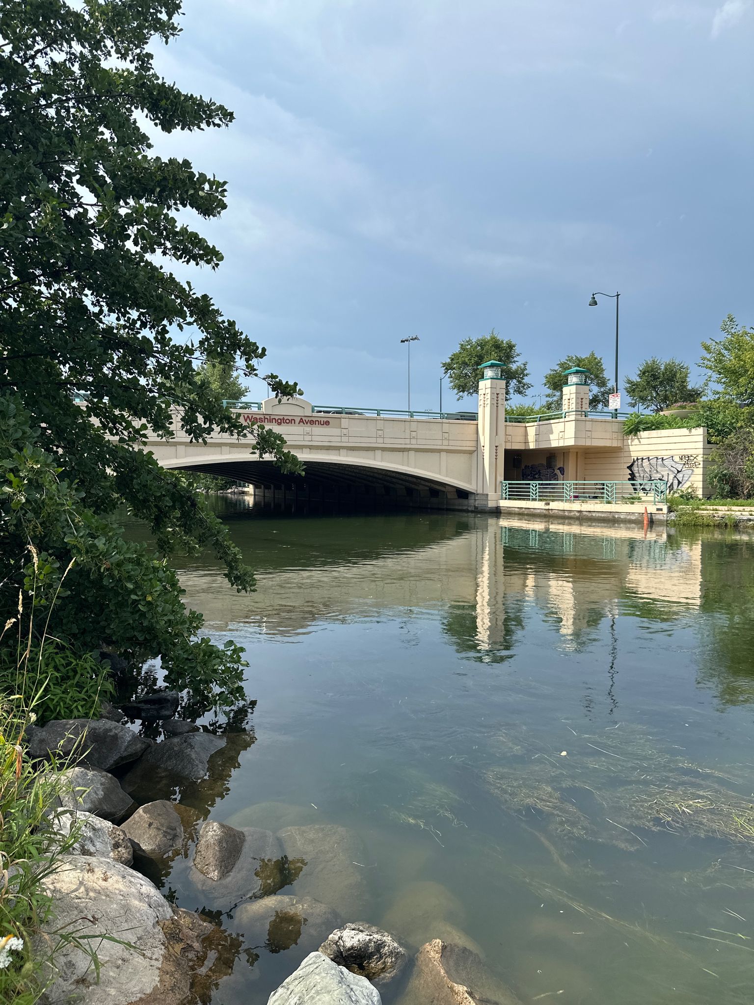 Large concrete bridge over a river, with rocky banks and cloudy sky. - Yahara River – Monona Terrace Rooftop loop from East Towne Mall