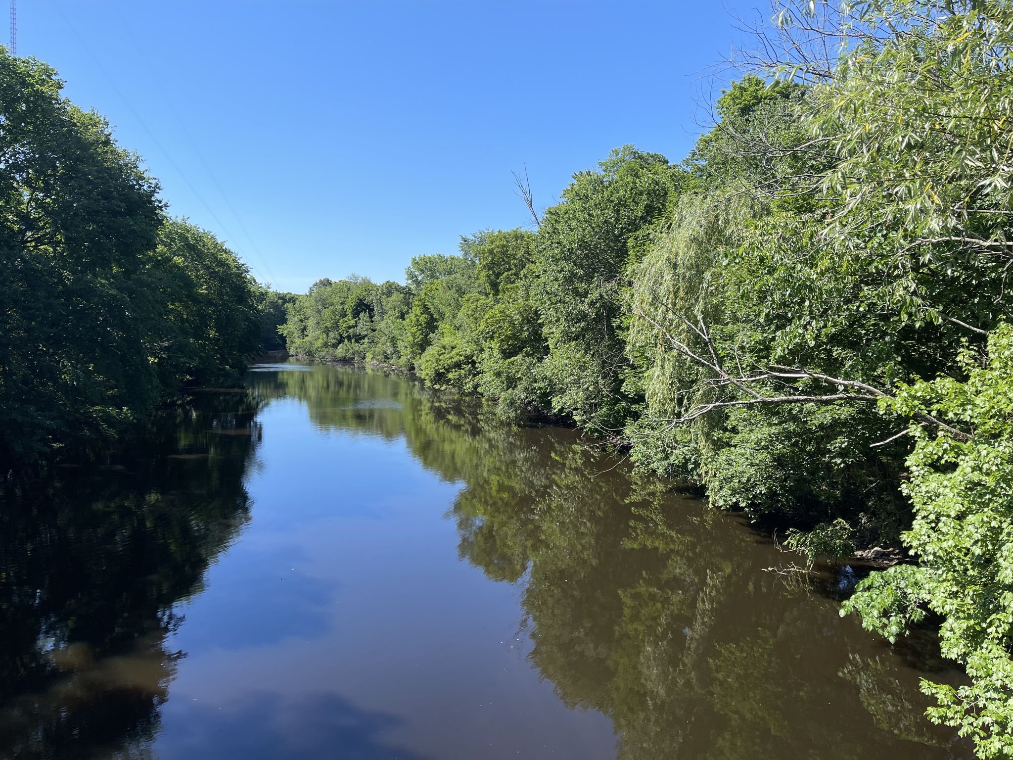 River with calm water, reflecting green trees under a clear blue sky. - Eliot to Hale Reservation loop