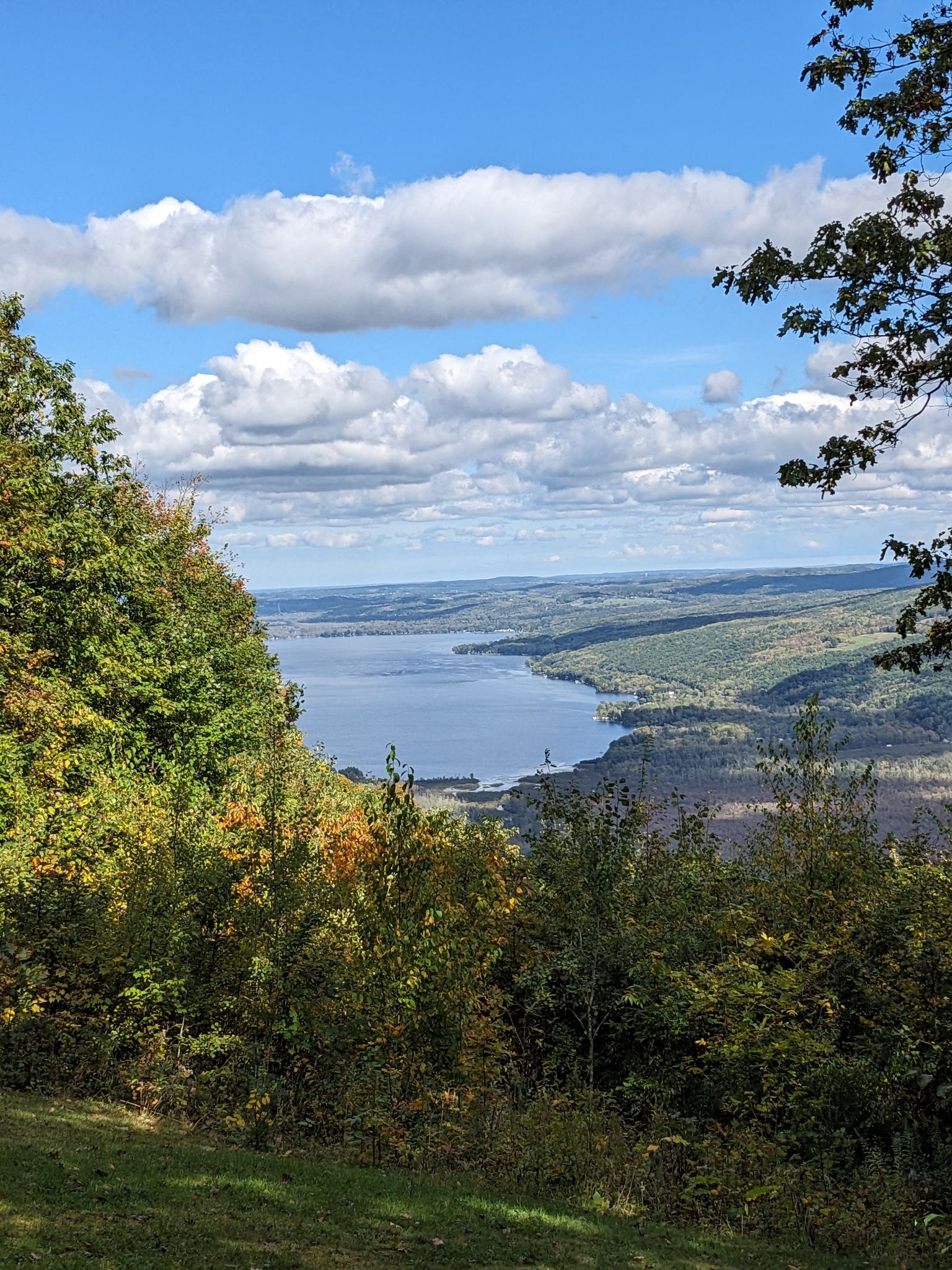 Panoramic view of a large lake surrounded by green and autumn-colored hills under a cloudy sky. - Bear Cub, Cannonball, Fox, Raccoon and Chalet Loop