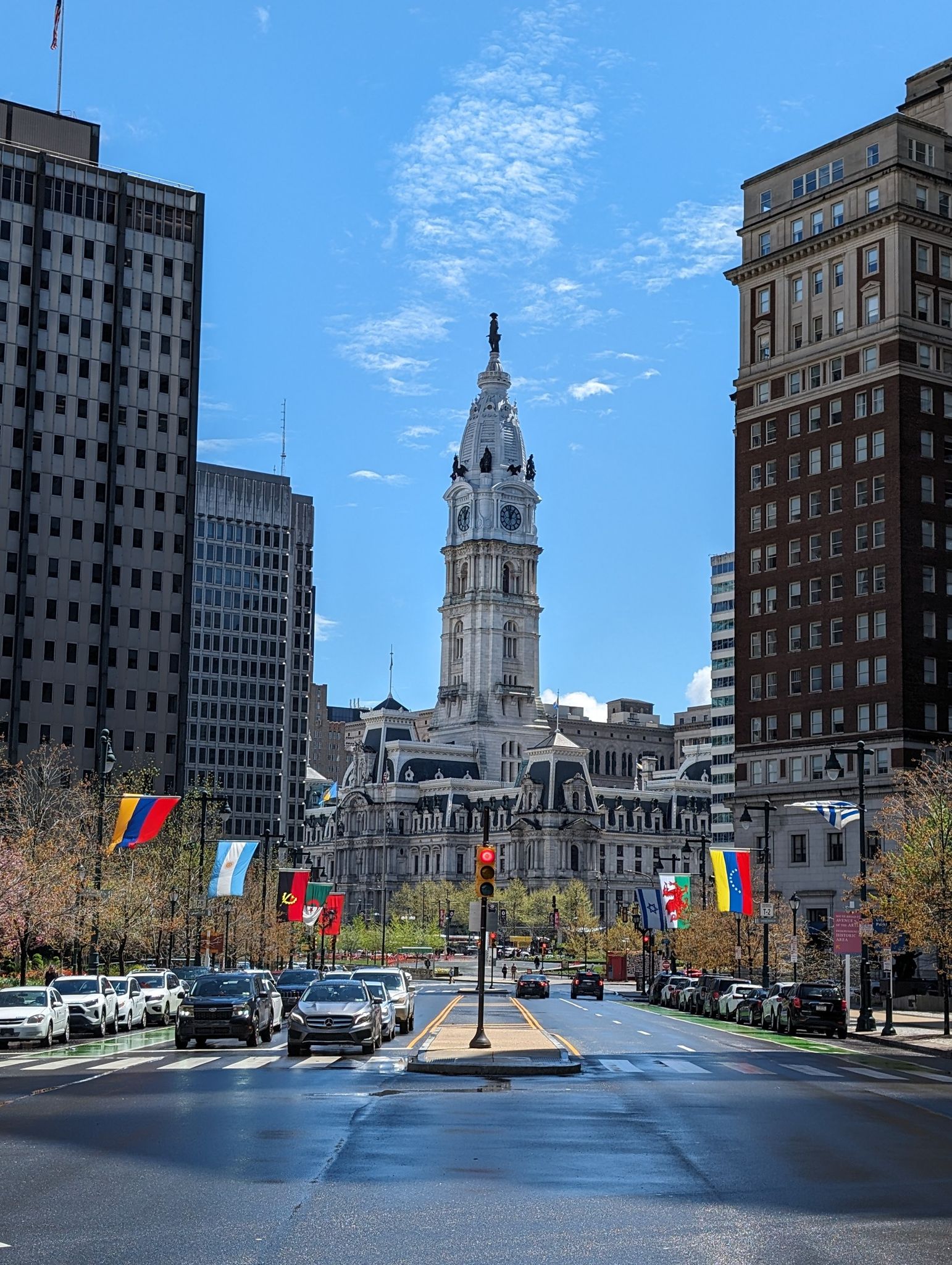 Ornate clock tower building at the end of a street flanked by tall buildings. - Reading Terminal Market – Rocky Statue loop from 2nd Street