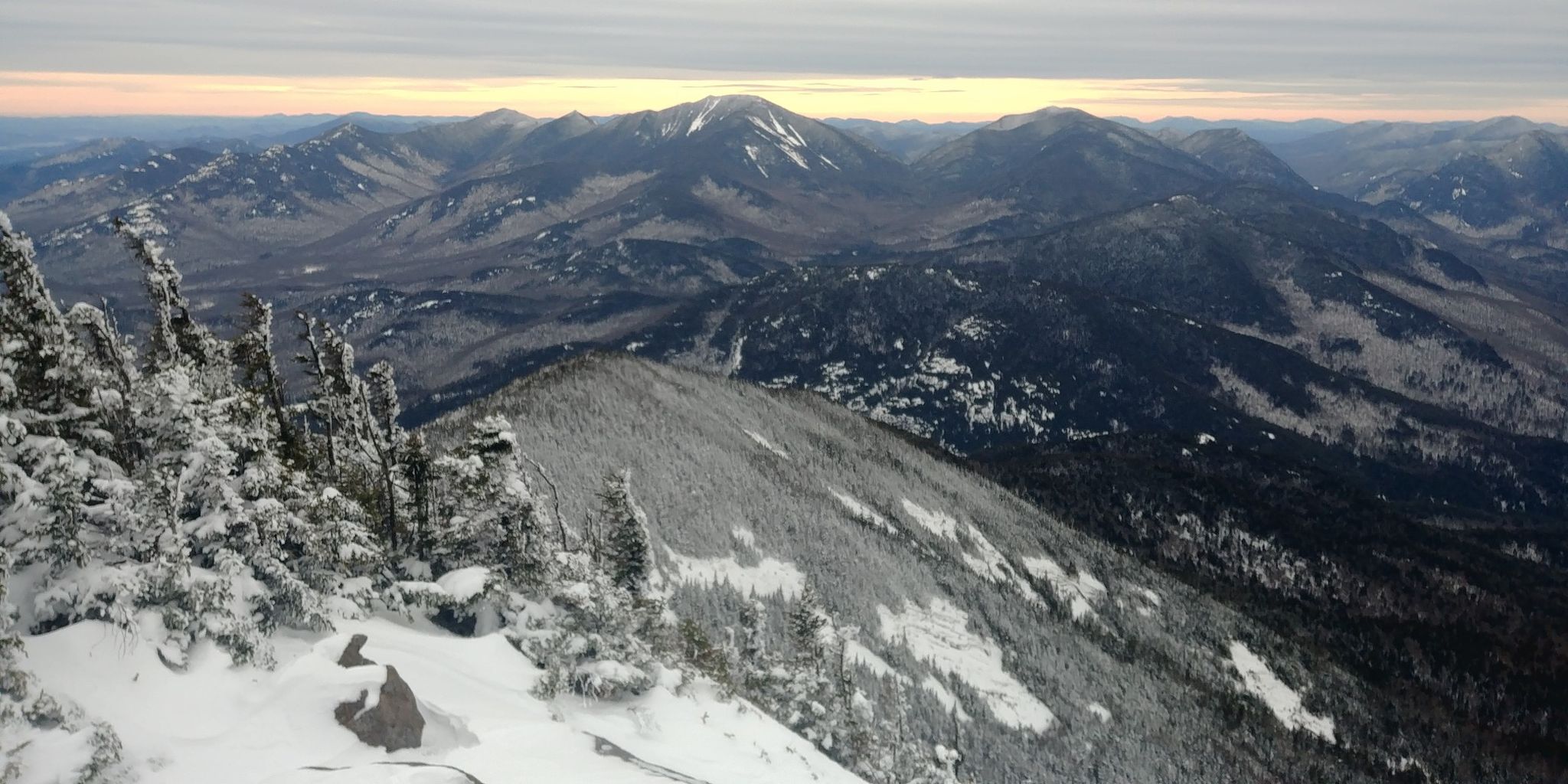 Icy trees and snowy mountain ridges at sunrise, with distant peaks. - Roaring Brook Trail