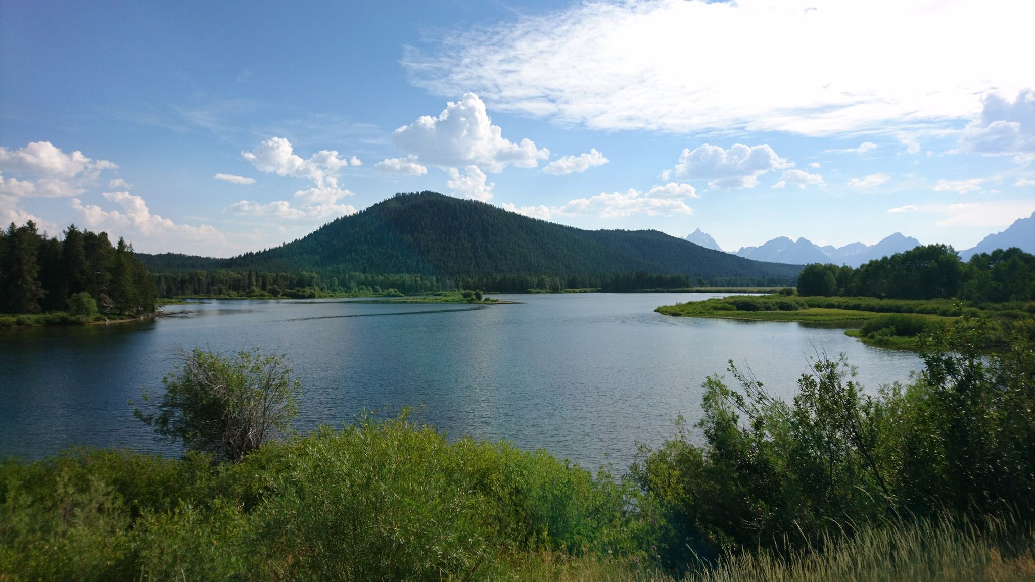 Calm lake surrounded by forested hills and distant mountains. - Great Divide Mountain Bike Route: Two Ocean Lake Loop