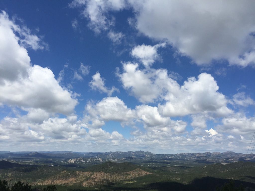 Expansive blue sky with white clouds over a vast, green and brown mountain landscape. - Creekside Trail/Ghost Canyon loop — Custer State Park
