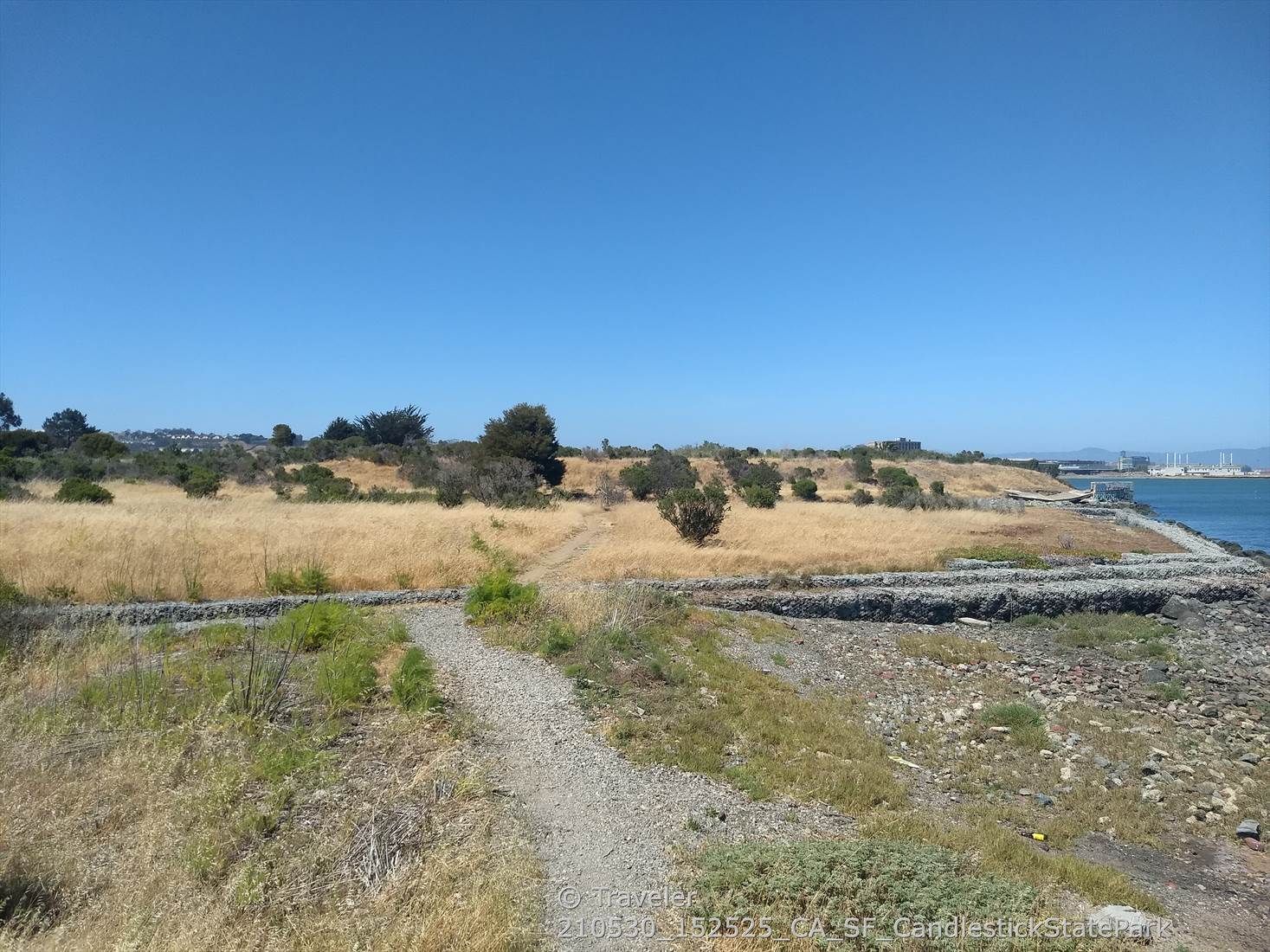 Dirt path through dry grass leading to a sunny bay. - Candlestick Point