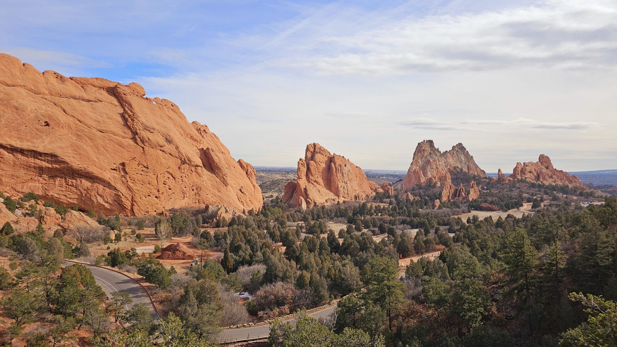 Panoramic view of red rock formations, green trees, and a winding road. - Palmer and Central Garden Loop Trail