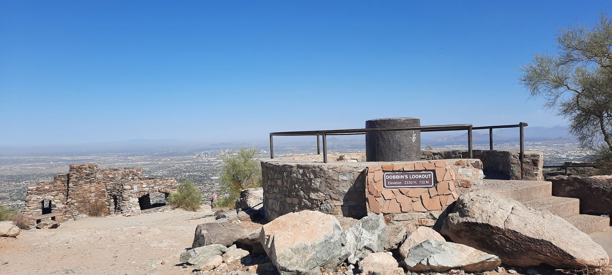 Stone observation deck with a metal railing overlooking a distant city. - South Mountain Preserve – Dobbins Lookout loop from Cesar Chavez High School
