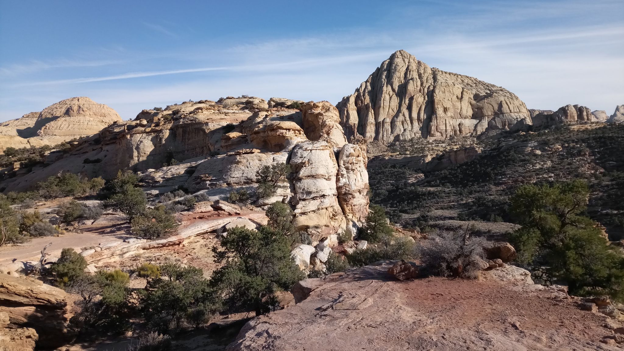 Pointed rock formation and other desert rock structures under a bright sky. - Hickman Bridge Trail