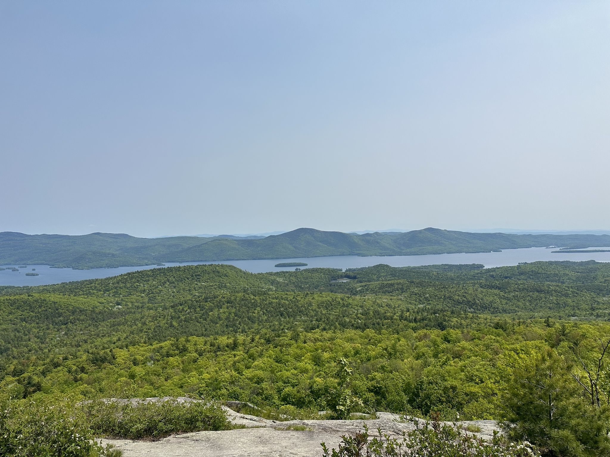 Broad view of a large lake surrounded by green forested hills. - Cat Mountain Blue Trail
