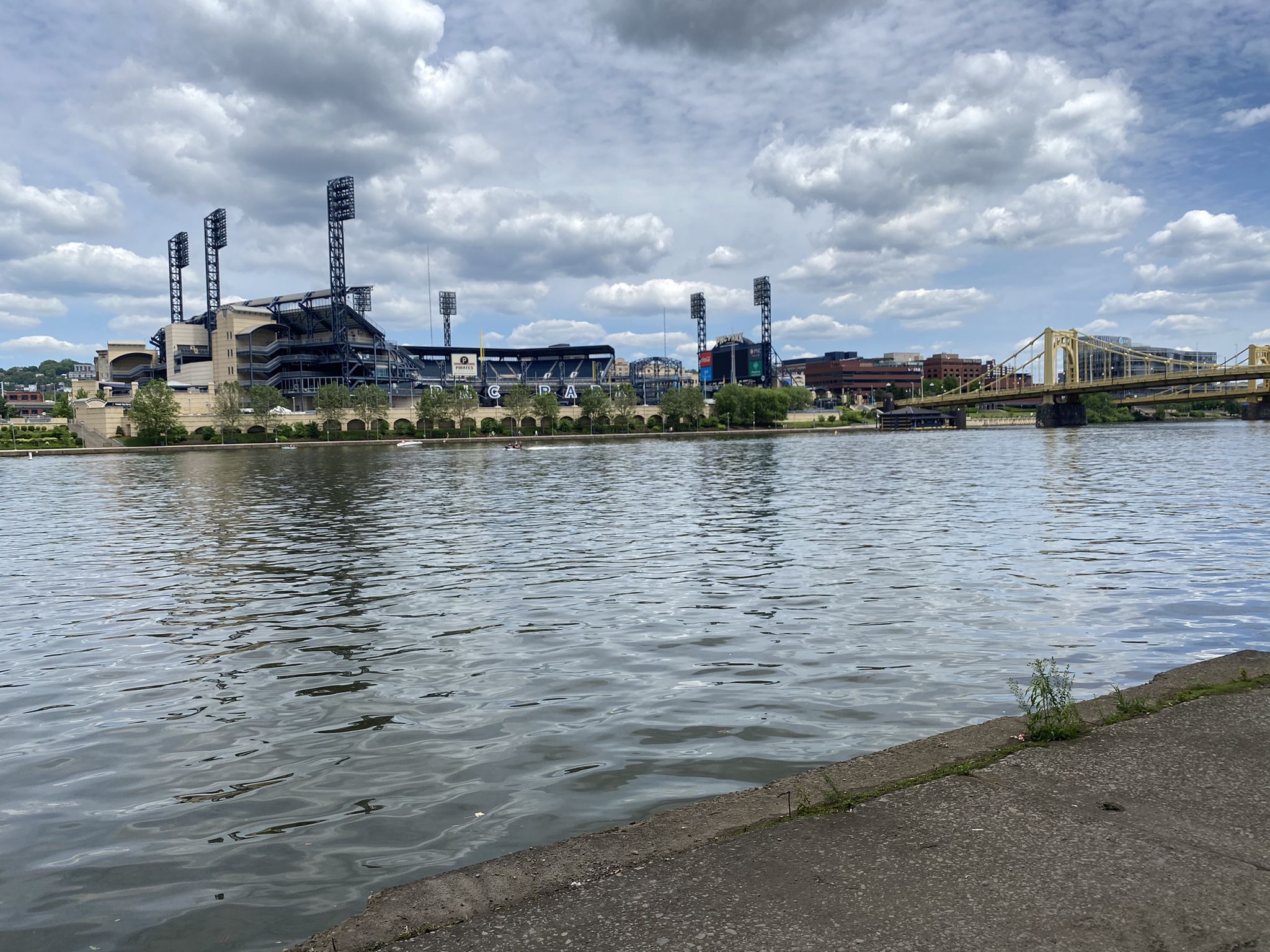 River view of a large stadium and bridge under a cloudy sky. - Three Rivers Heritage Trail