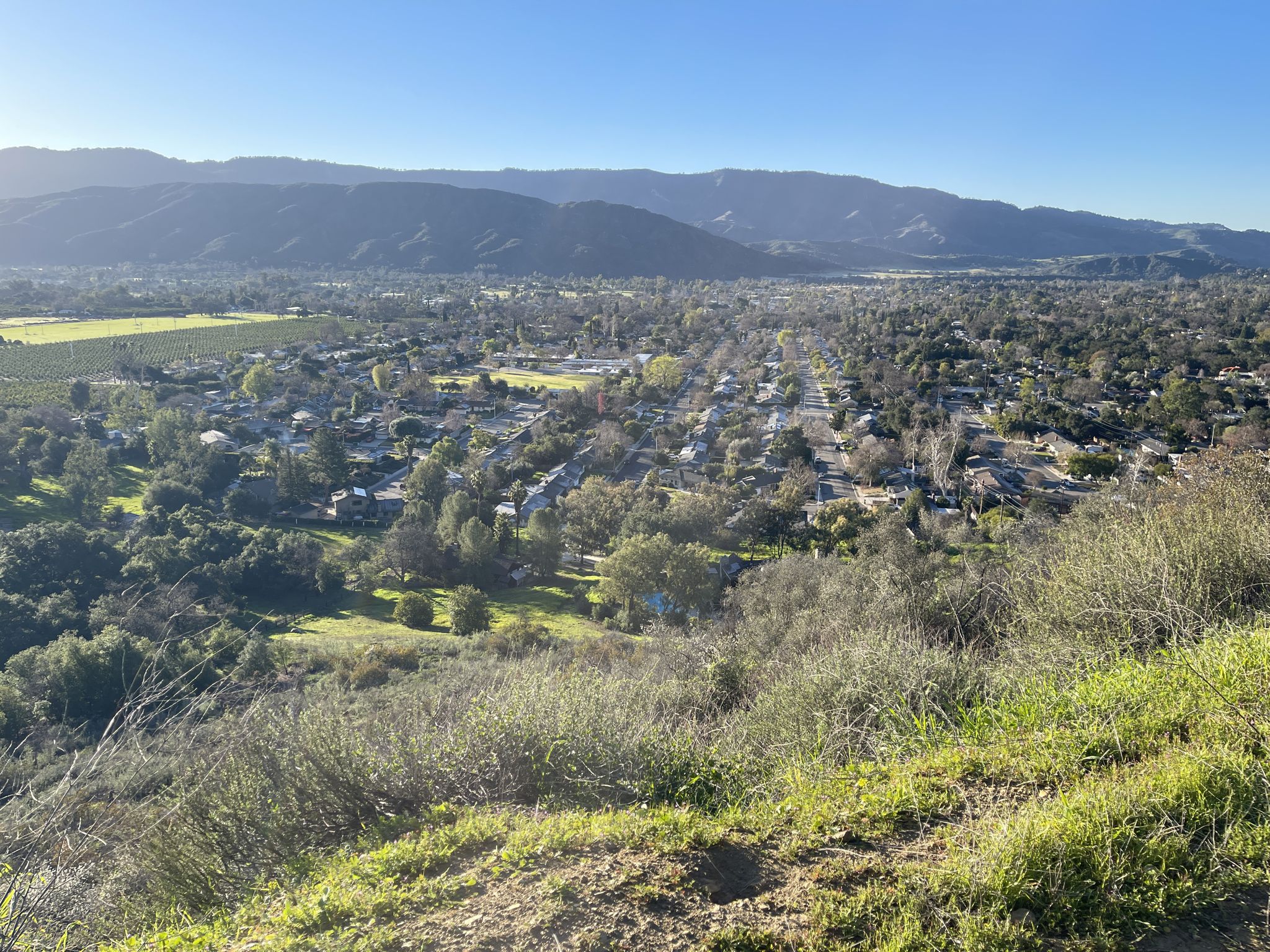 Overlook of a town and valley with mountains under a clear, sunny sky. - Ojai Bell Tower – Shelf Road loop from Oak View
