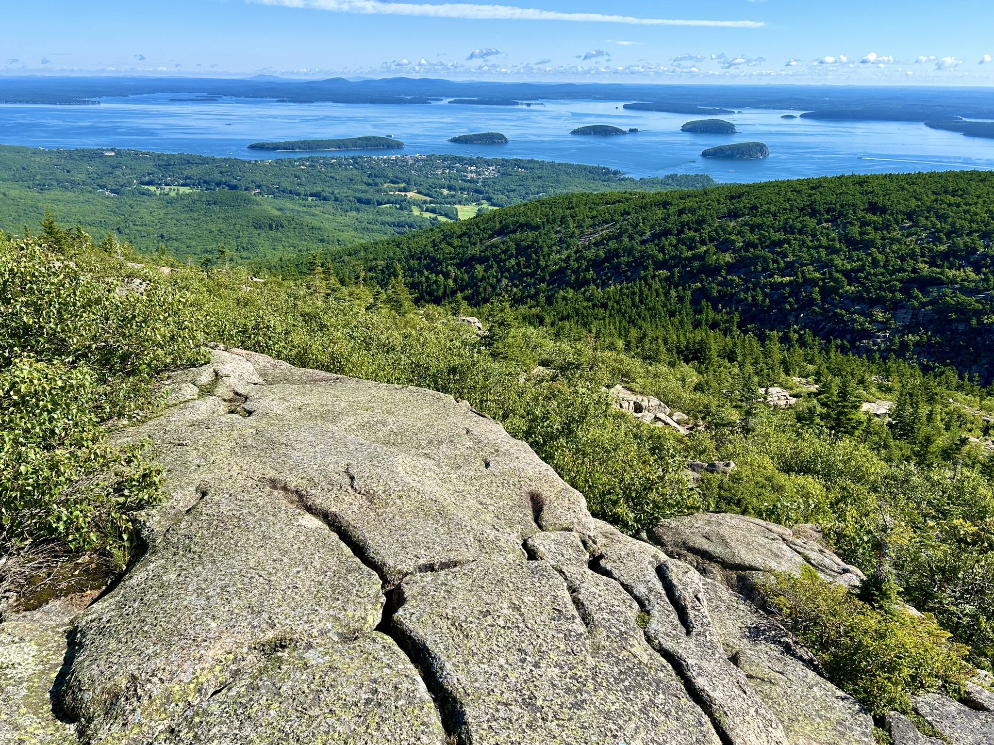 Rocky mountain top overlooking a vast ocean with many islands, sunny. - Cadillac Mountain loop