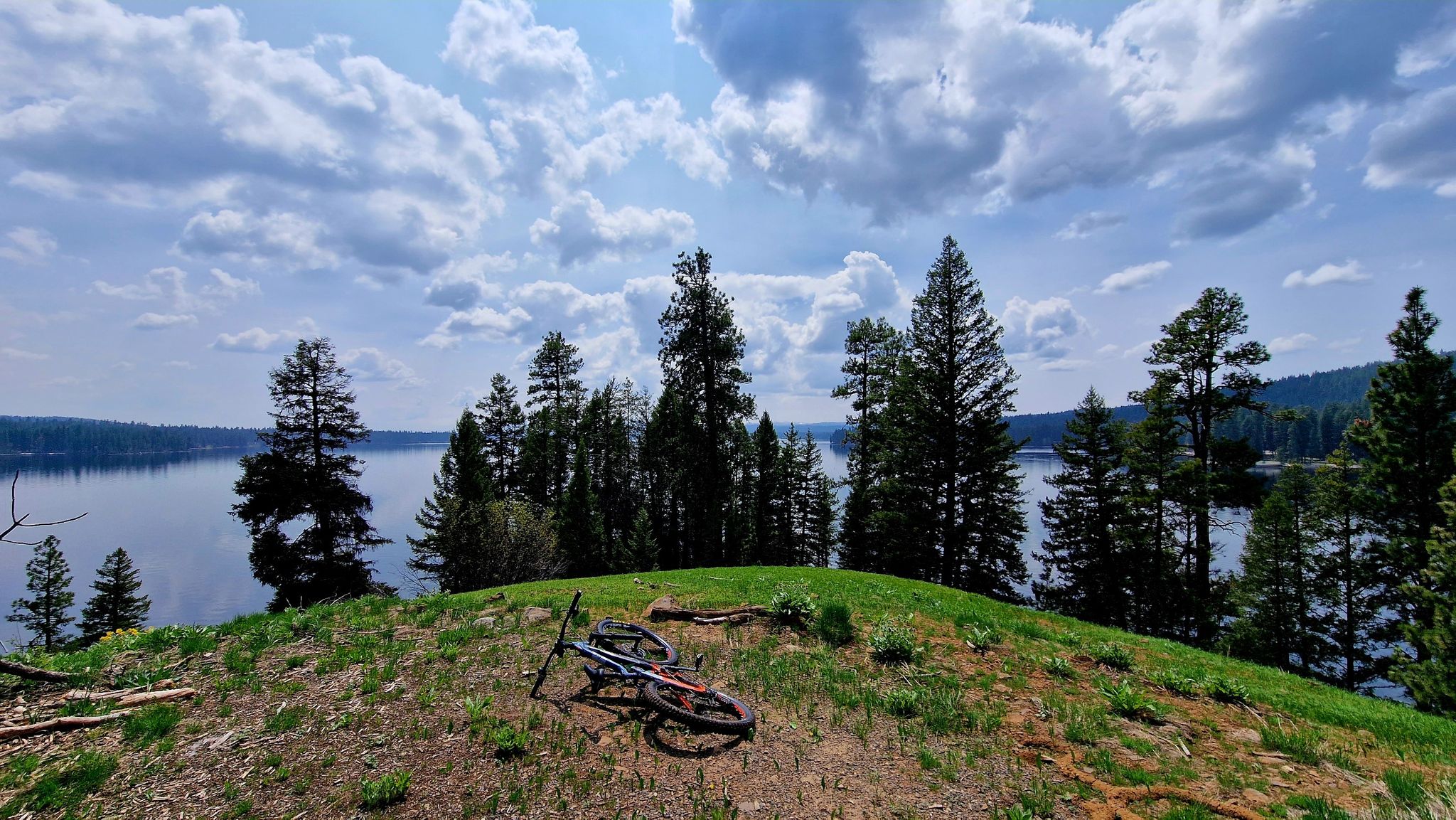 Mountain bike on a grassy hill overlooking a calm lake and forest. - Huckleberry Trail – Payette Lake loop from RV Campground