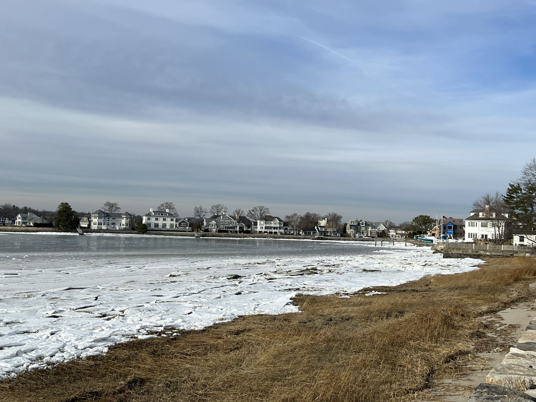 Icy water with houses along the shore under a cloudy winter sky. - St. Catherine of Siena Church – Greenwich Point Beach loop from Mamaroneck