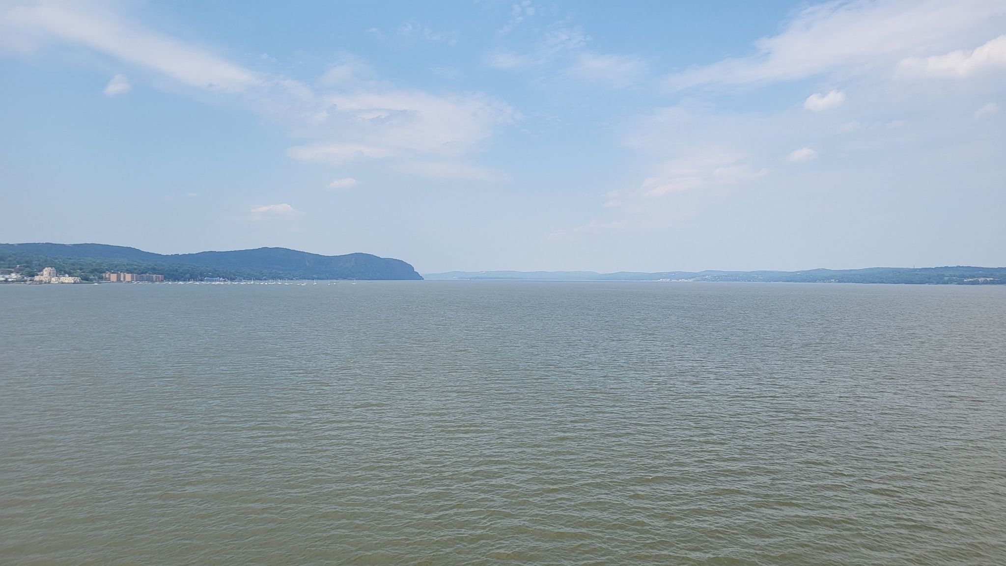 Expansive body of water with distant green hills under a bright, cloudy sky. - Roadbike loop from Nyack