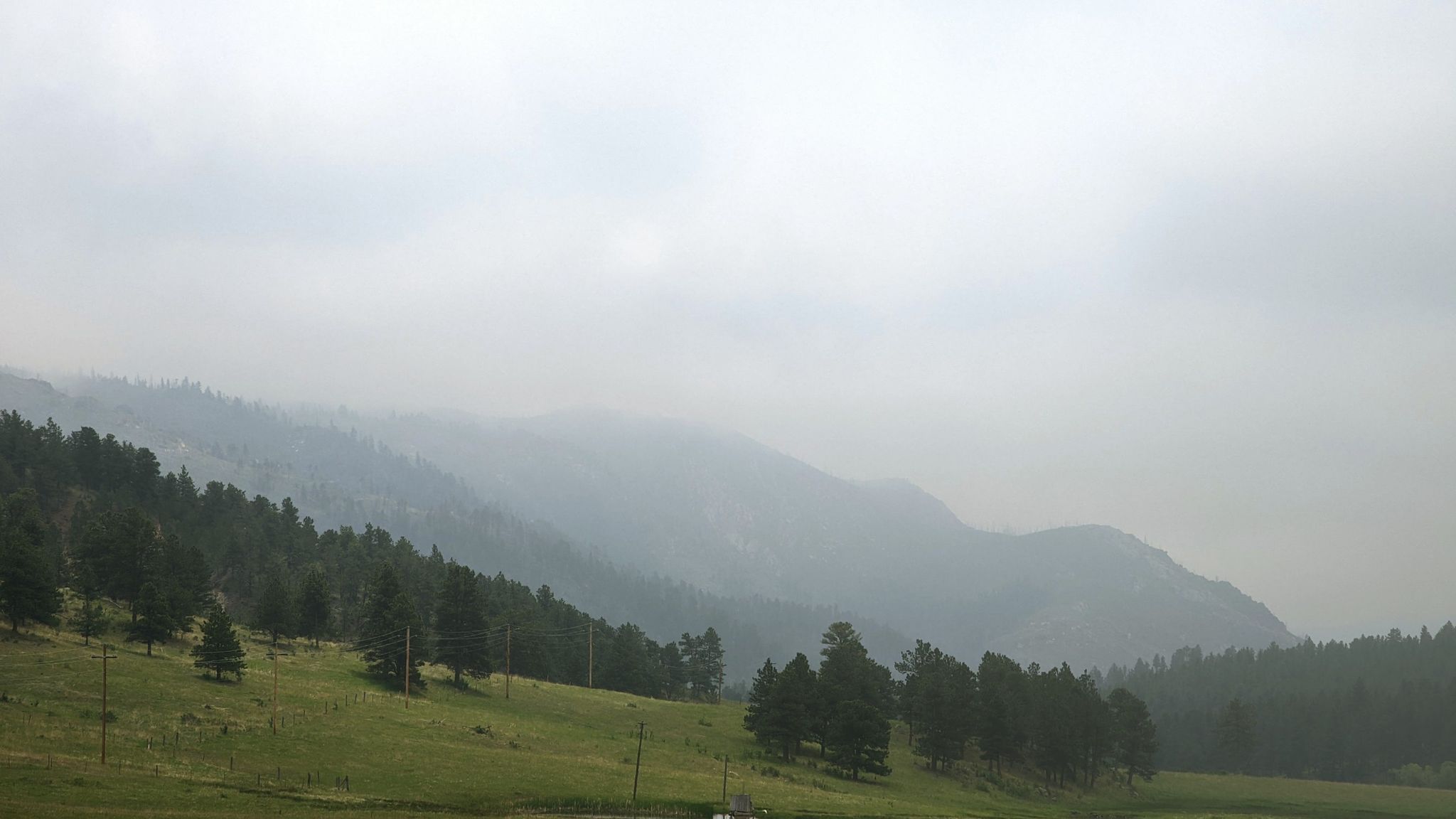 Misty green mountains and pine forests under a gray, overcast sky. - White Rock loop from Stove Prairie