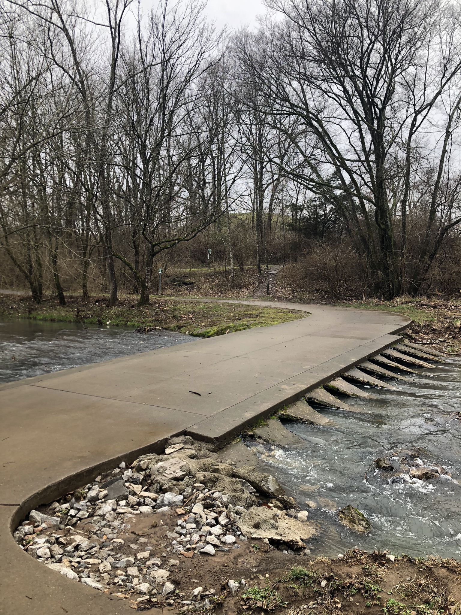 Concrete path crossing a shallow stream with bare trees under an overcast sky. - Boiling Springs Mounds – River Park Trail loop from Holt Knobs