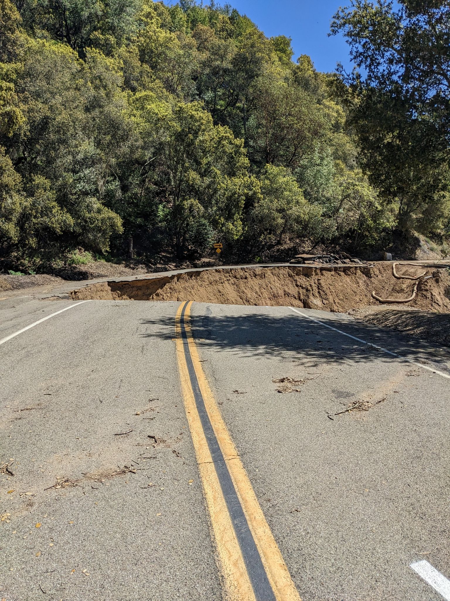 A paved road with a large section collapsed, revealing exposed earth. - Redwood Road loop from Castro Valley