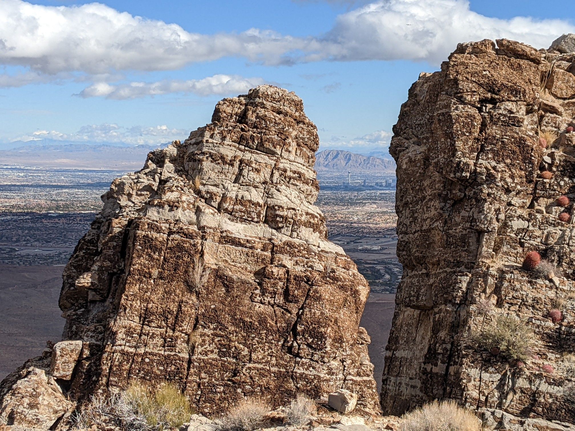 Two large rock formations frame a distant city and mountains under a cloudy sky. - Las Vegas Overlook Loop