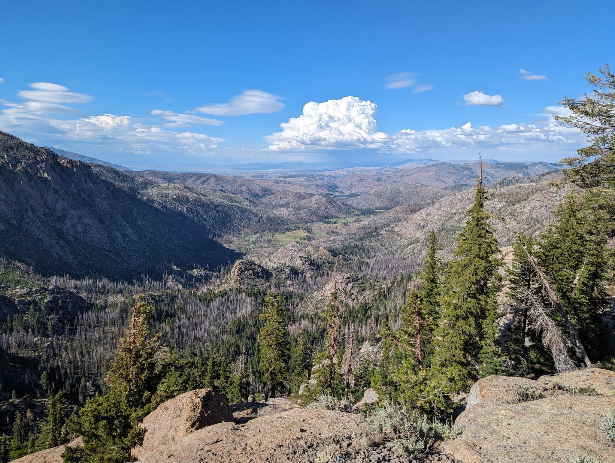 Expansive mountain vista overlooking a deep valley with forests under a cloudy sky. - Raymond Lake via Wet Meadows Trailhead