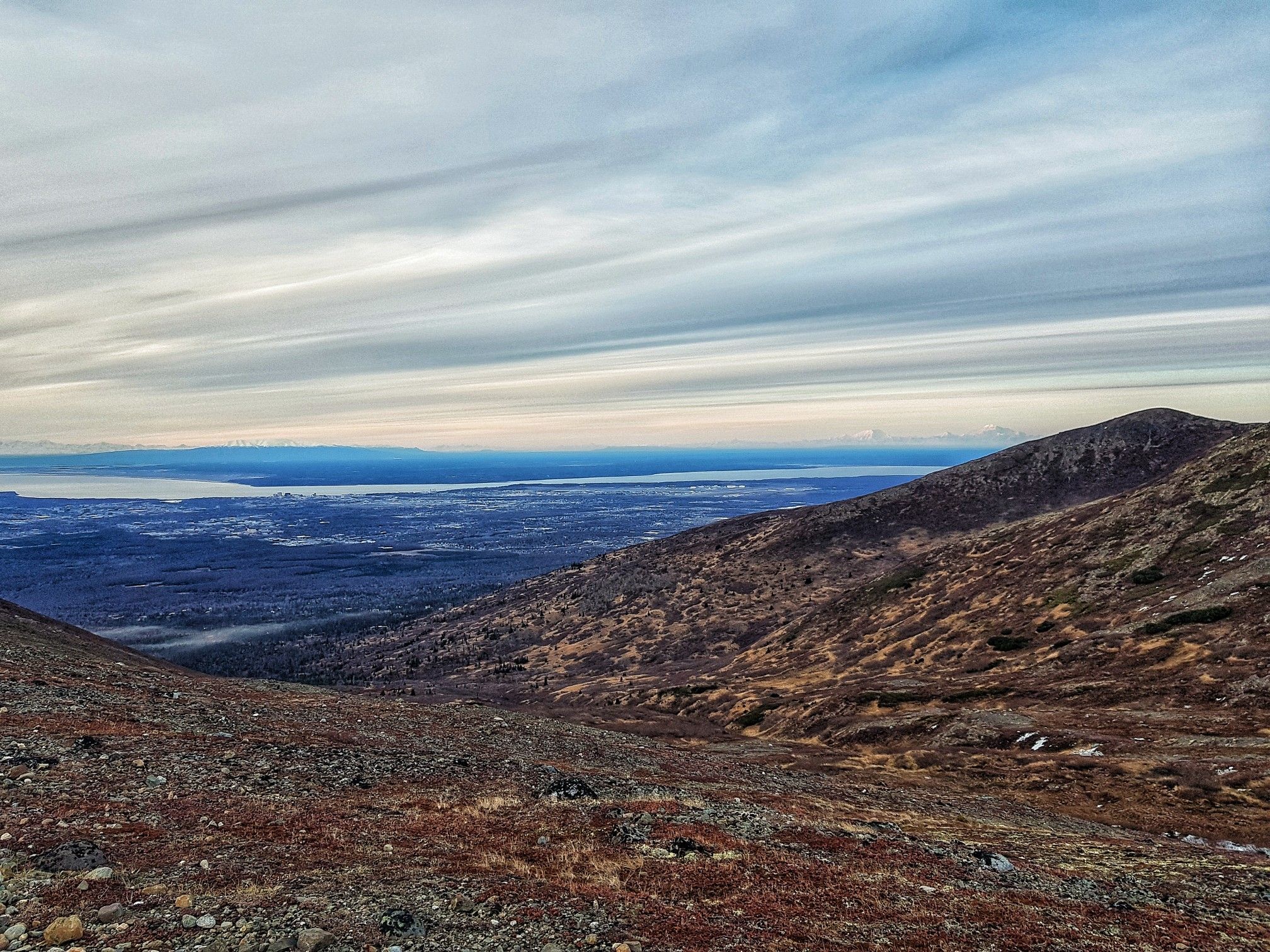 Wide view from a barren mountain slope towards a distant body of water. - Wolverine Peak via Basher Trail