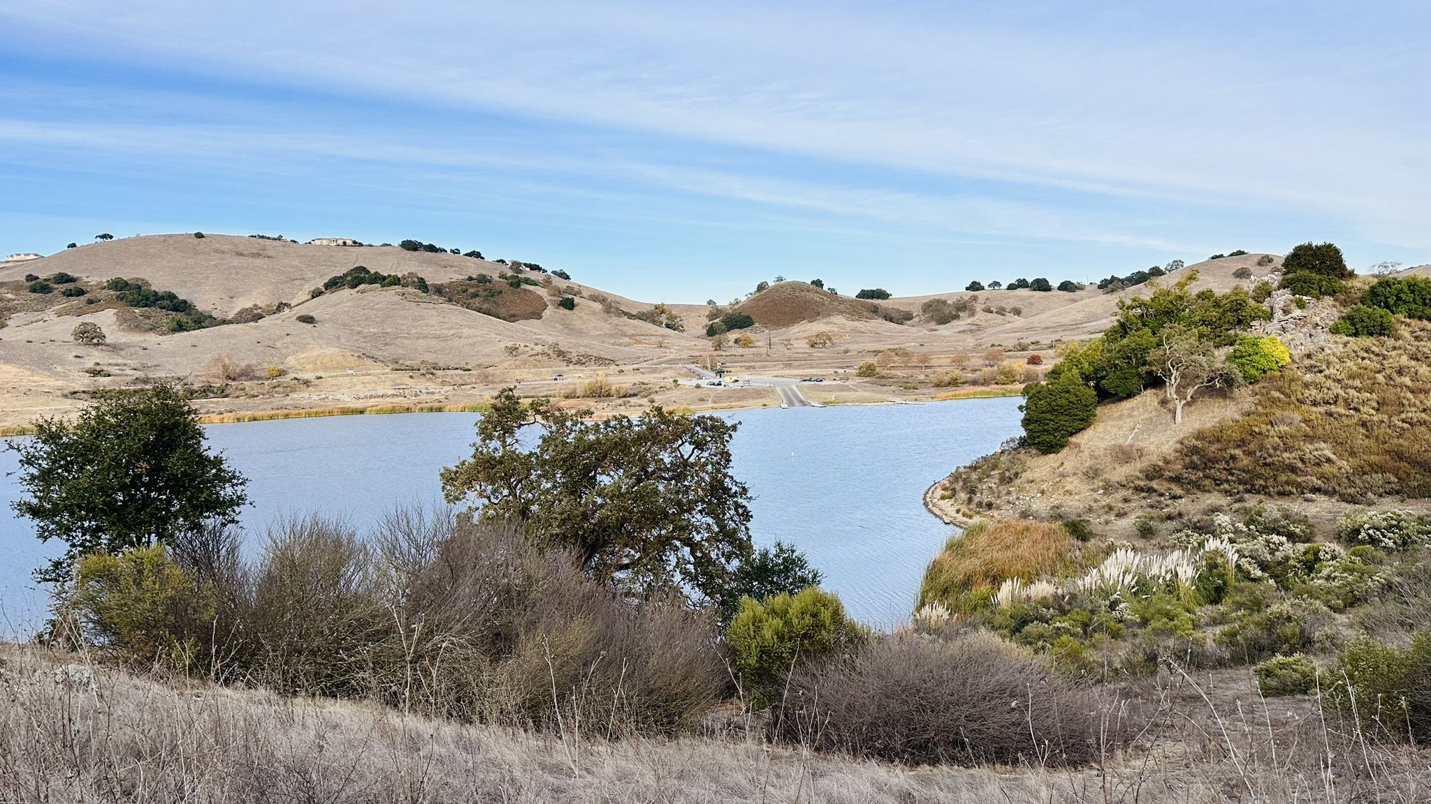 Calm lake surrounded by dry hills and sparse trees under a blue sky. - Bald Peaks loop via Oak Cove Trail & Chisnantuk Peak Trail