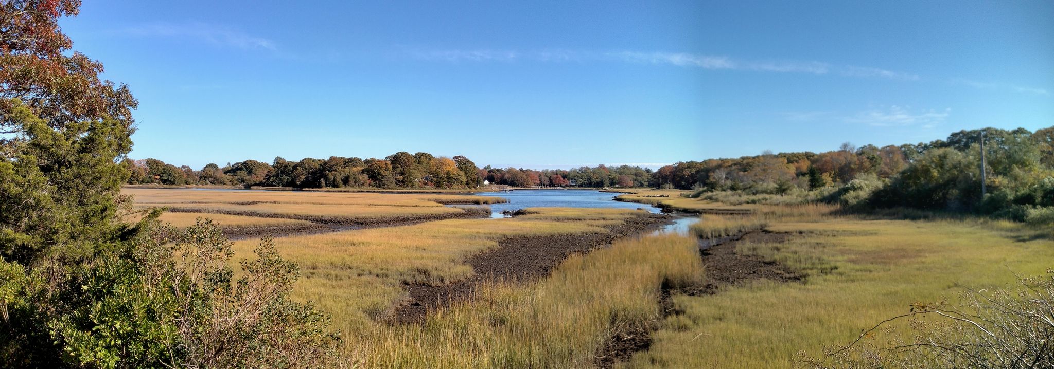 Panoramic view of a winding river through golden marshland under a clear blue sky. - Beaches around New Bedford