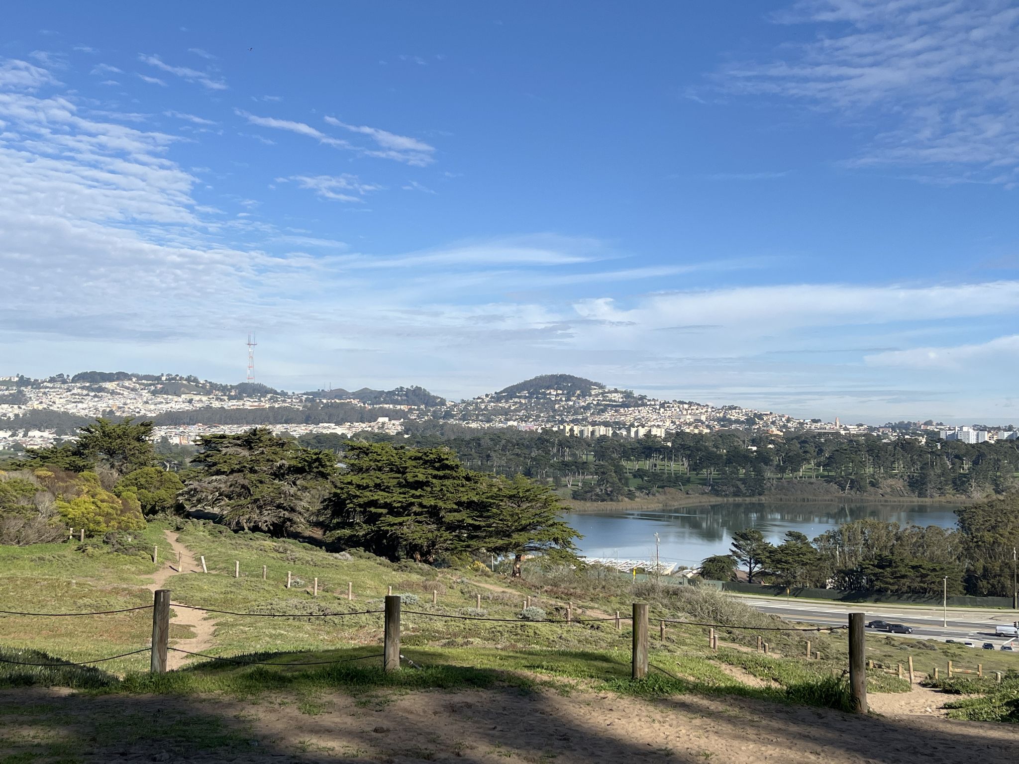 A lake with a distant city and hills under a bright blue sky. - Fort Funston Coastal Trail