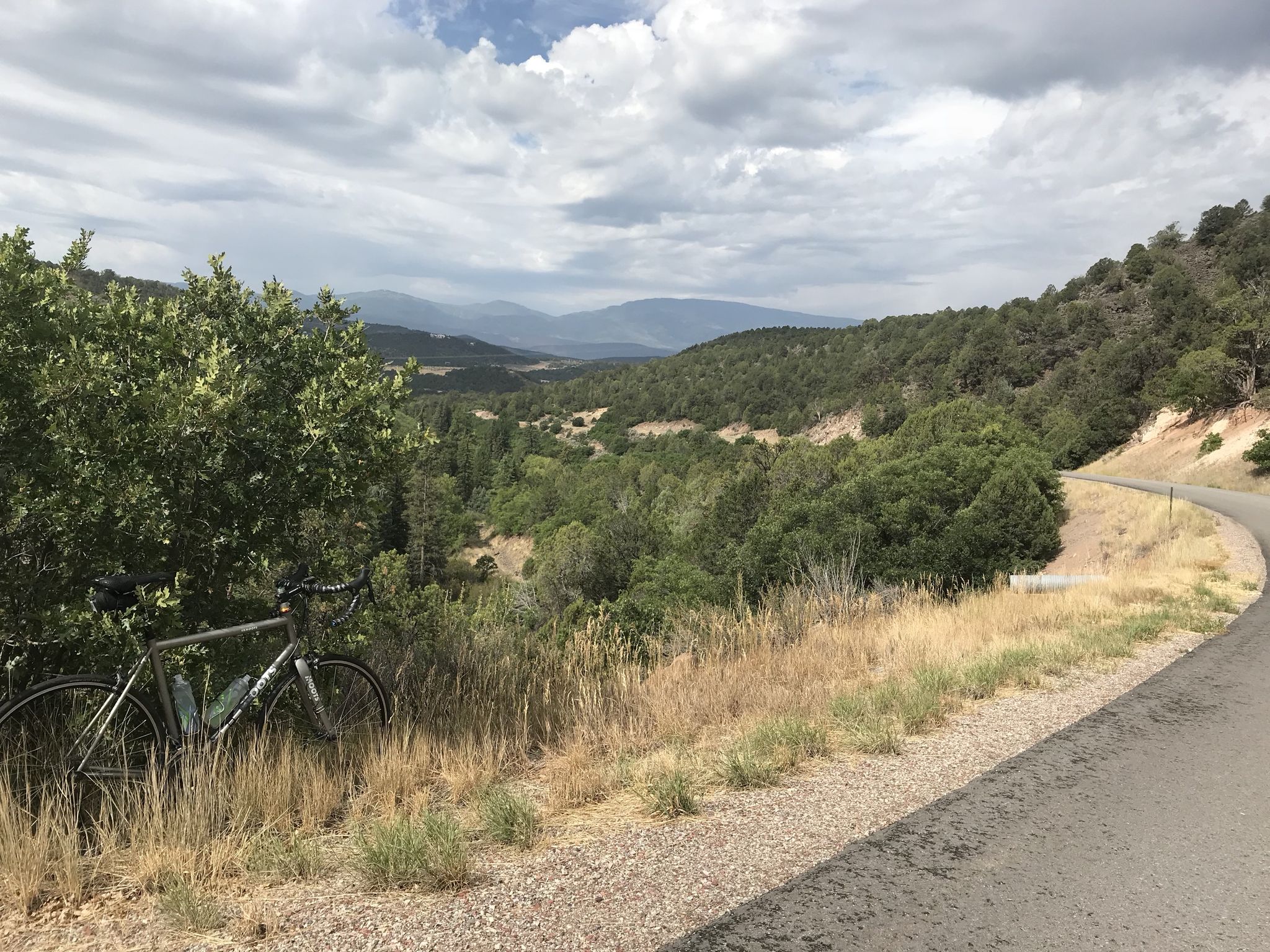 Bicycle parked by a winding road overlooking a forested valley under cloudy skies. - Old Coulter Creek School House – Fisher Creek Trailhead loop from CMC Park and RIde