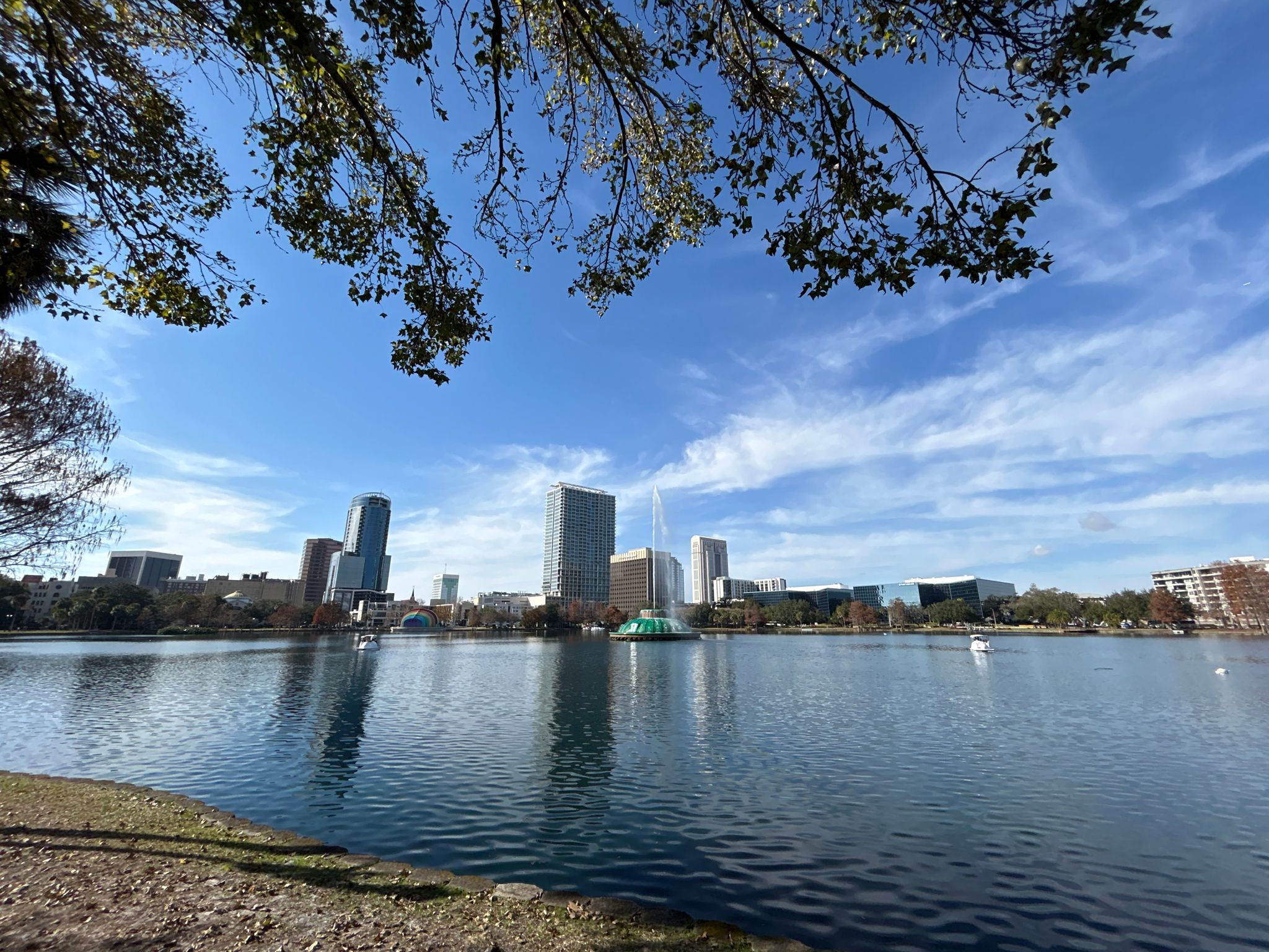 Wide view of a lake with city skyline under a bright blue sky. - Lake Eola Park loop