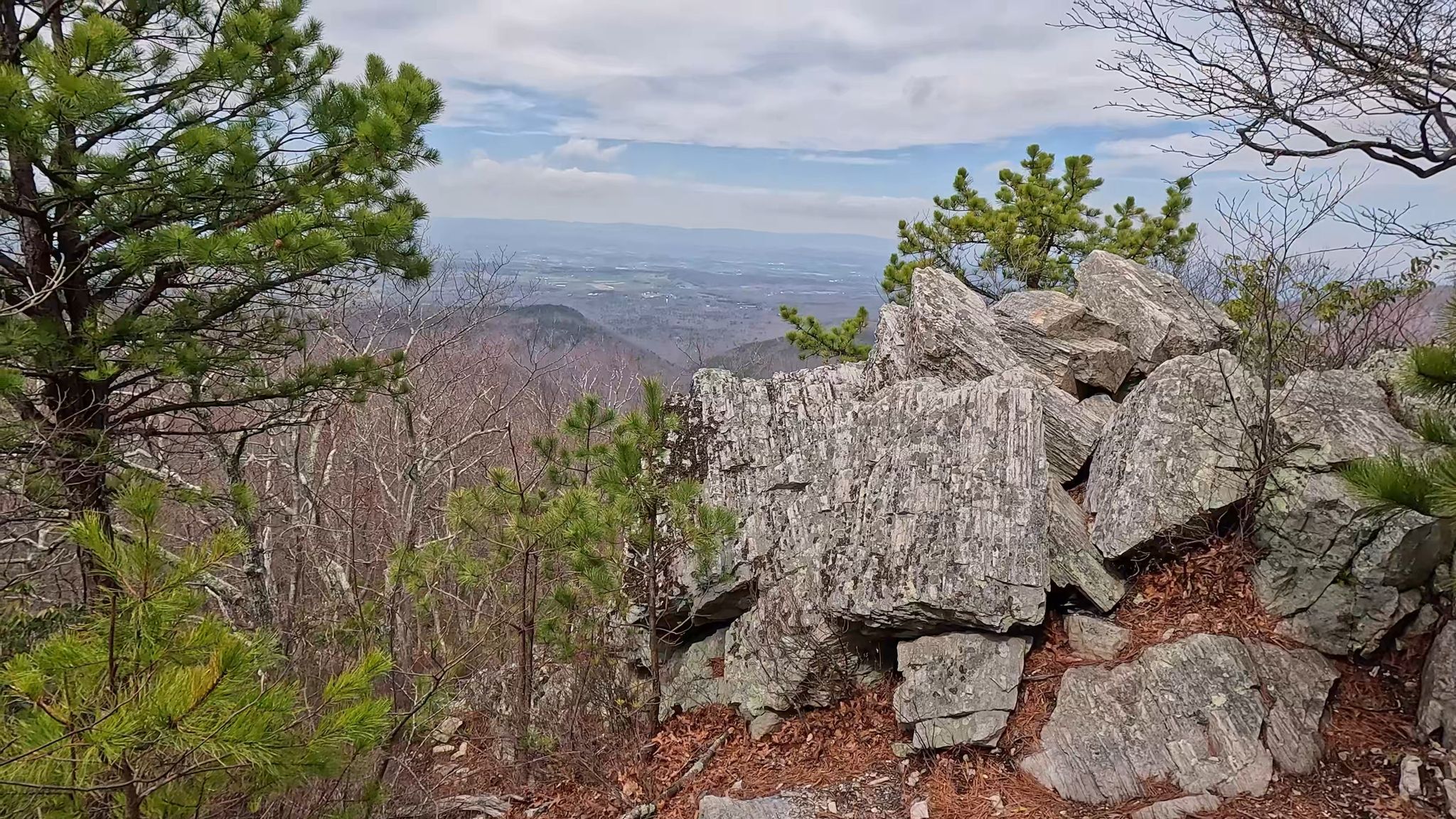 Large gray rock formations and pine trees overlooking a hazy valley. - Calvary and Chimney Rocks Trail
