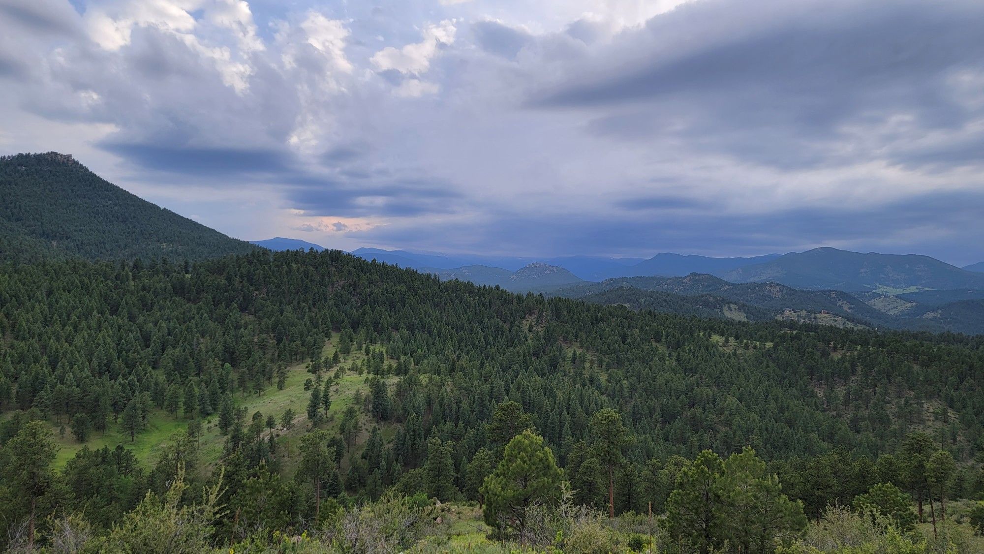 Expansive forested hills under a dramatic, cloudy sky. - Meadow View Loop