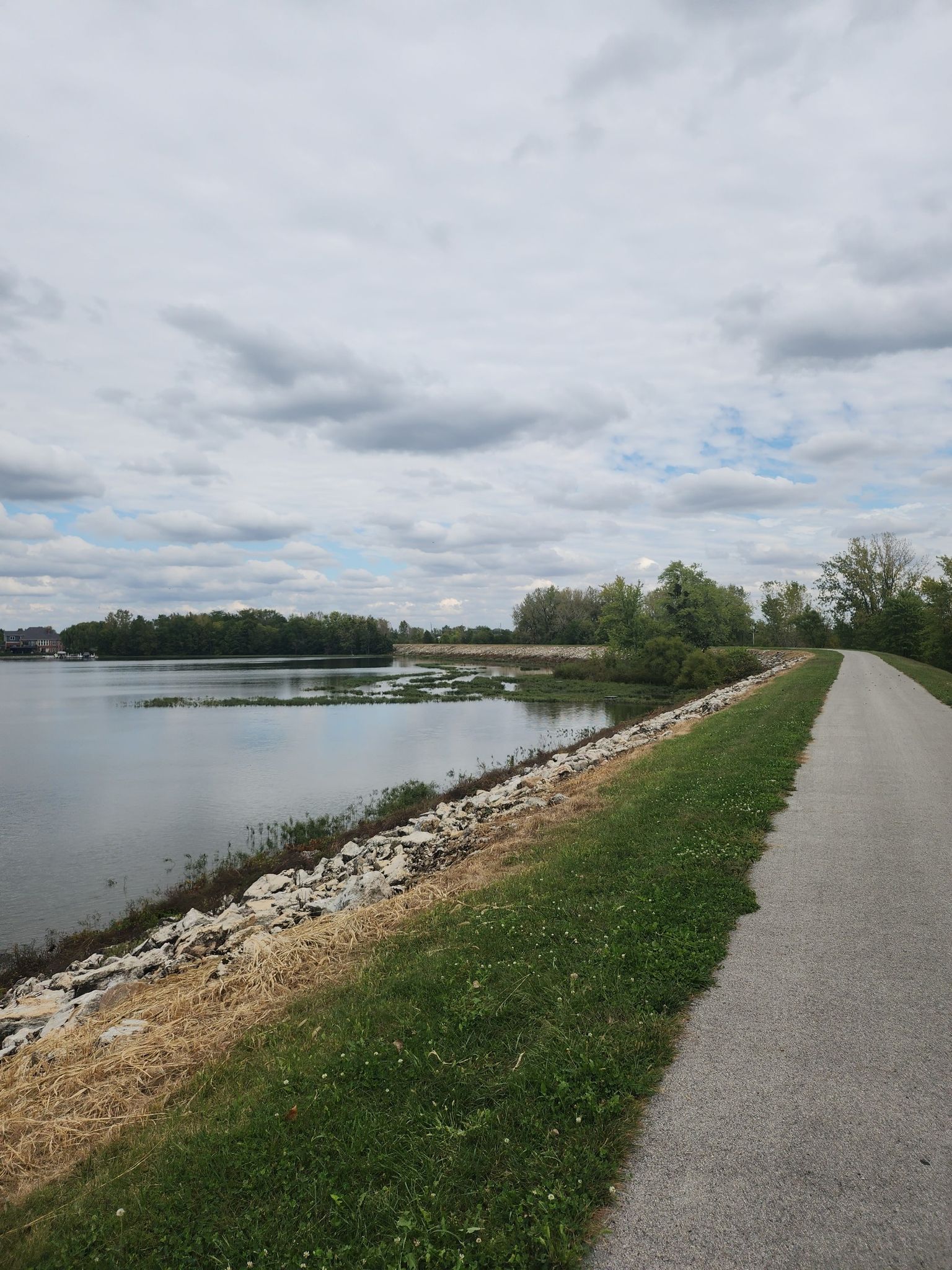Paved path alongside a calm lake under an overcast sky. - Morse Park loop