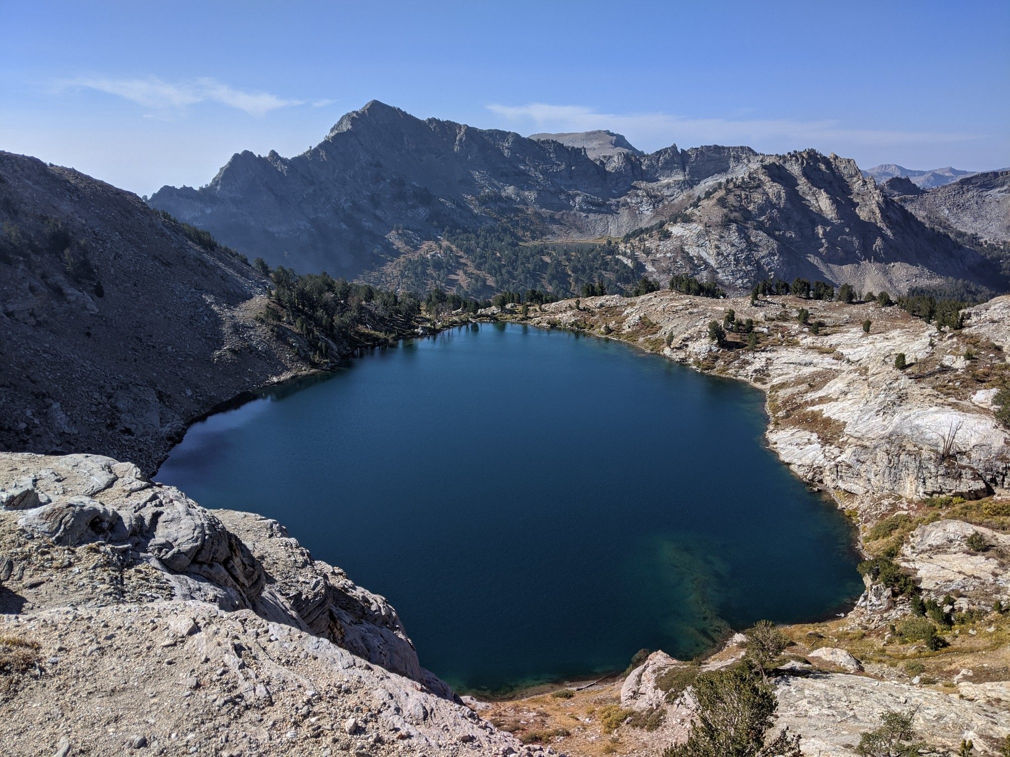 Dark blue alpine lake surrounded by barren rocky mountains under a clear sky. - Ruby Crest Lakes Loop