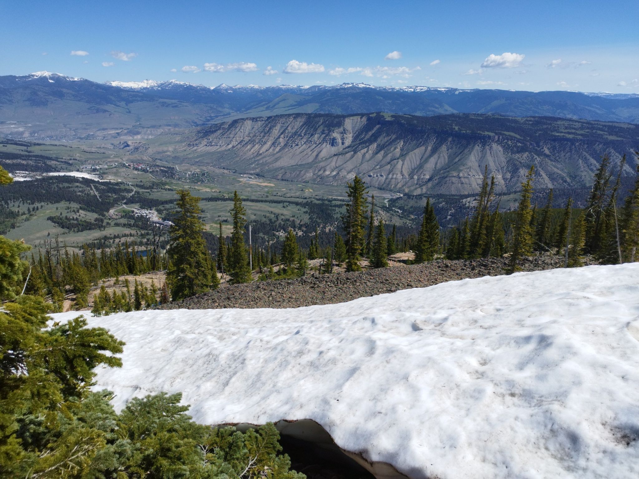 Patch of snow on a mountain slope overlooking a vast valley and distant peaks. - Bunsen Peak loop from Bunsen Peak