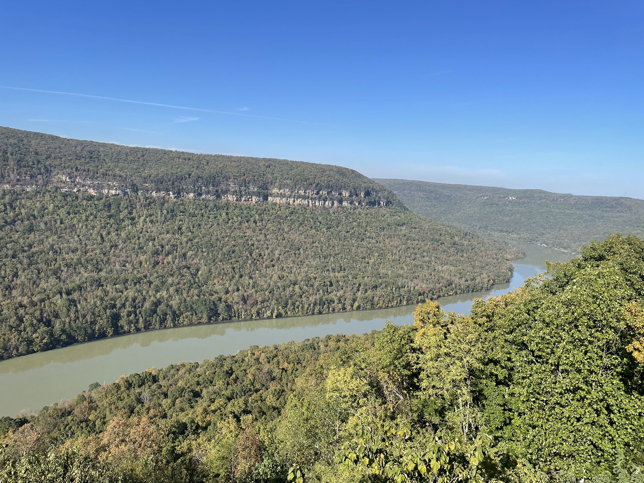 Wide river winding through a forested valley under a clear blue sky. - Raccoon Mountain Reservoir loop