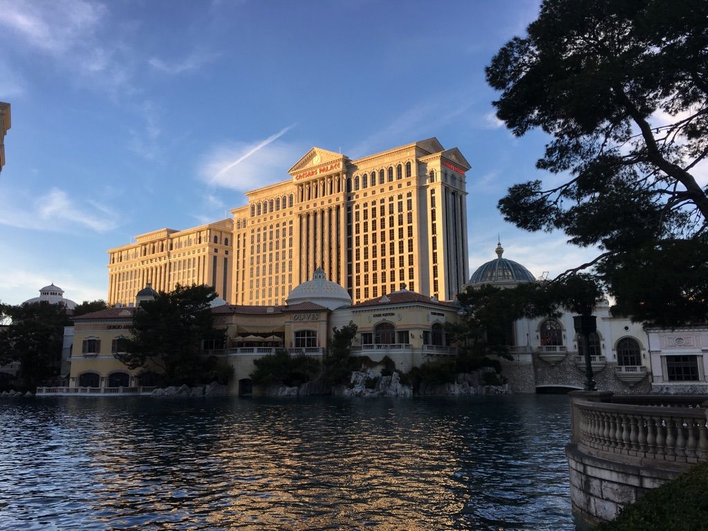 Ornate building and lake with trees, bathed in warm, golden light. - Fountains of Bellagio – The Venetian Resort loop from Caesars Palace/Flamingo