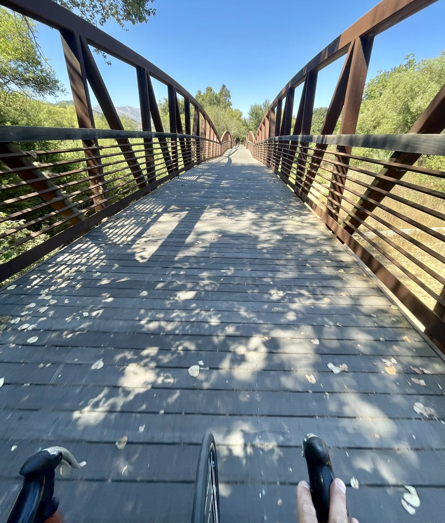 First-person view of a cyclist on a wooden bridge under a bright blue sky. - San Antonio Creek Bridge – Big Rock Preserve loop from Big Rock Preserve