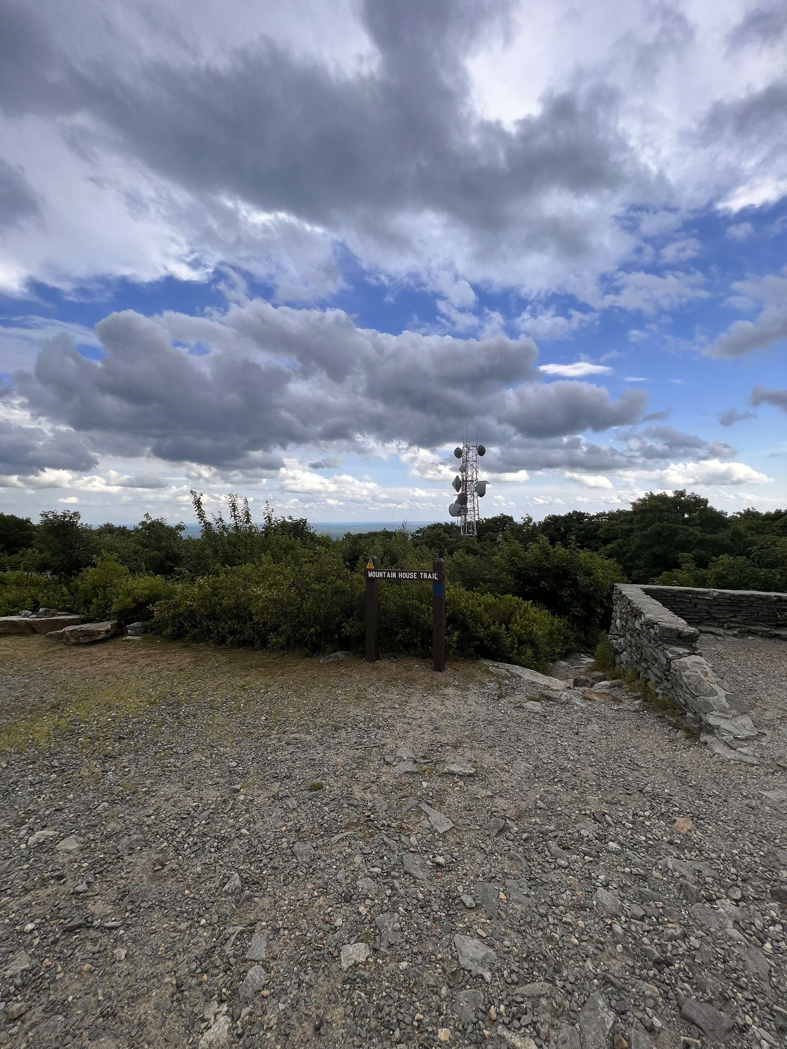 A trail sign and communication tower on a cloudy hilltop vista. - Echo Lake, High Meadow and Jack Frost Trail Loop