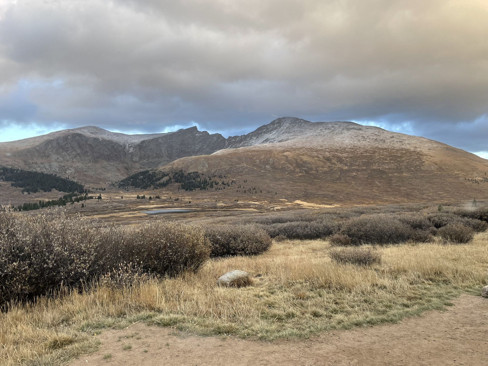 Wide view of rugged mountains and valleys under a dramatic, cloudy sky. - Guanella Pass Scenic Drive