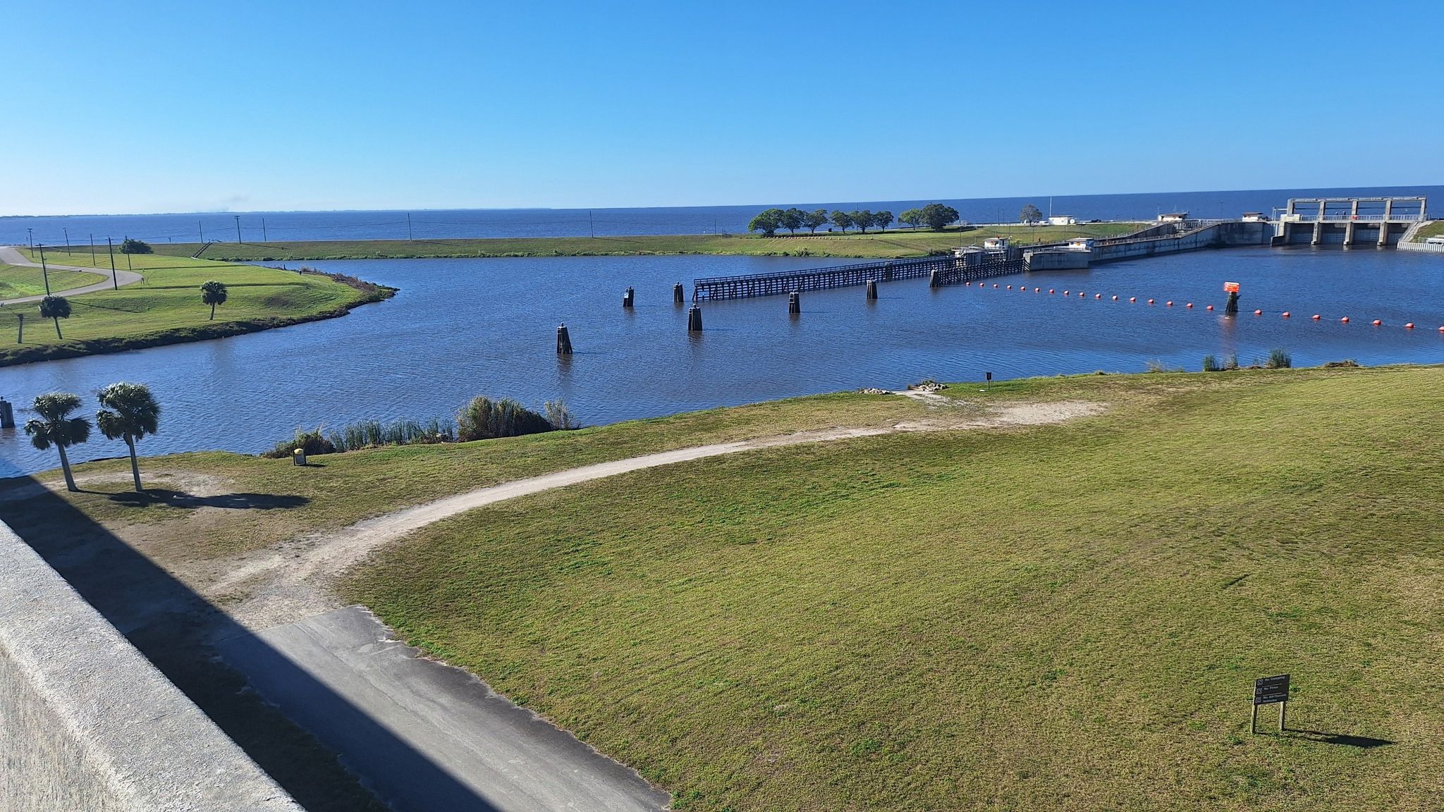 Wide view of a large lake with a dam and green grassy banks. - Lakeside Ranch STA via Conners Highway loop