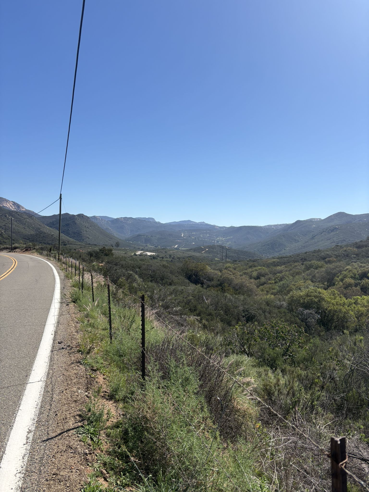 Roadside view of vast green valleys and distant mountains under a blue sky. - Lyons Valley loop