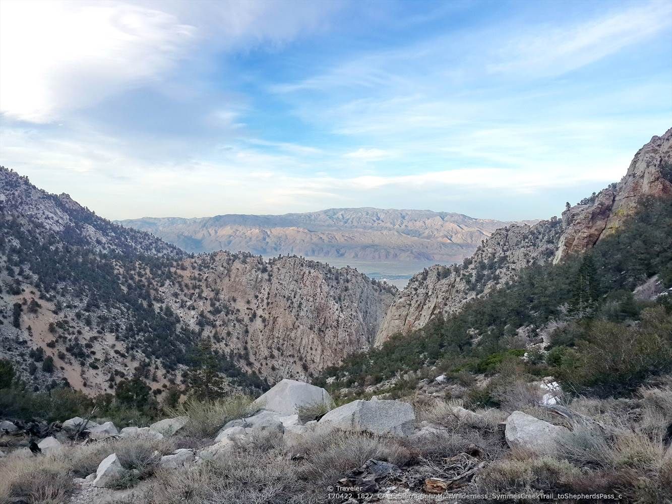 A vast mountain landscape with a deep valley and distant peaks under a blue sky. - Shepherd Pass Trail