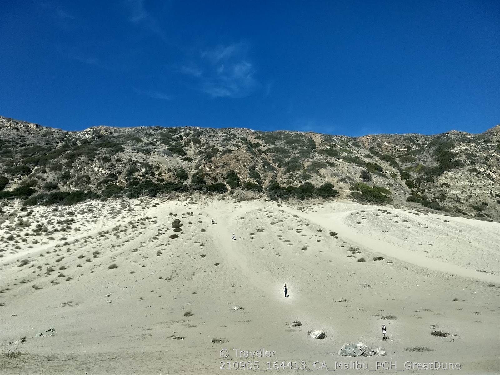 Vast sandy slope with a person, leading to a rocky mountain. - Circle X Ranch – Sandstone Peak Trailhead loop from Neptune's Net