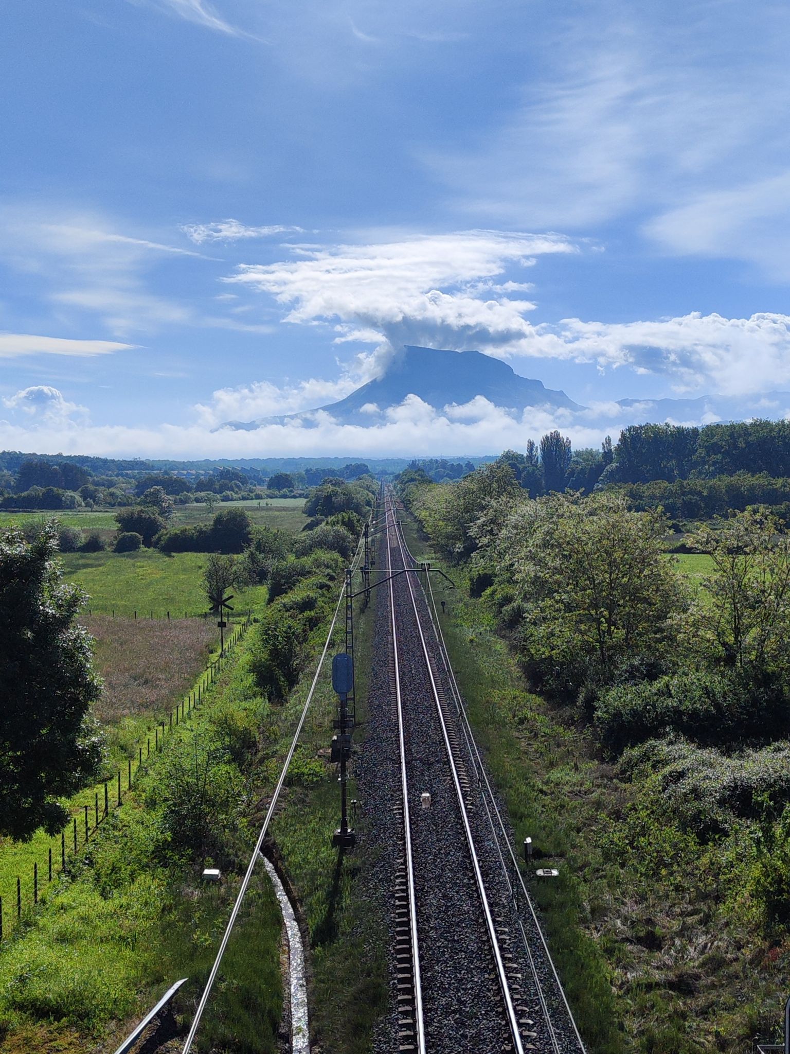 Vista de la línea férrea rectilínea con el macizo de San Donato al fondo