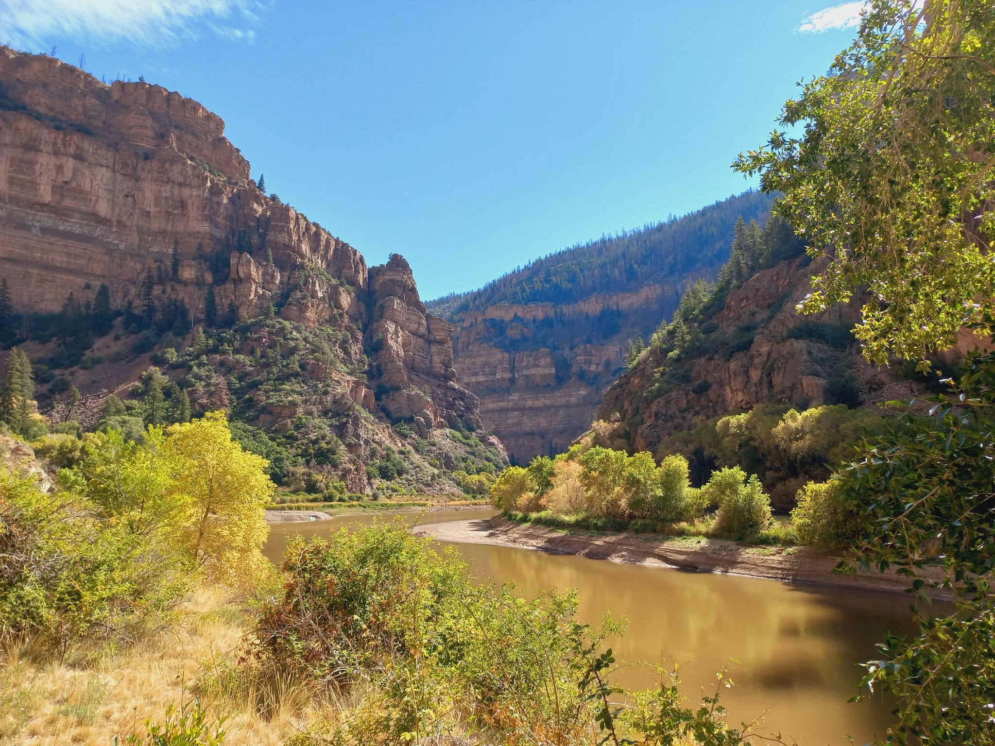 River winding through a deep canyon with steep rock walls and green trees. - Hanging Lake Trail