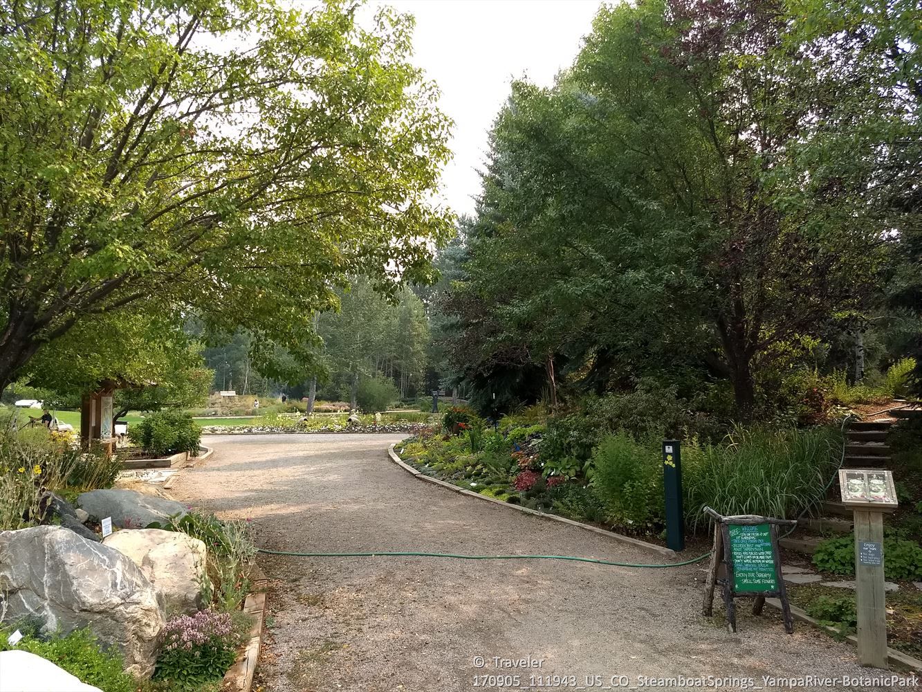 Gravel path winding through a botanical garden with diverse plants and trees. - Yampa River Core Trail