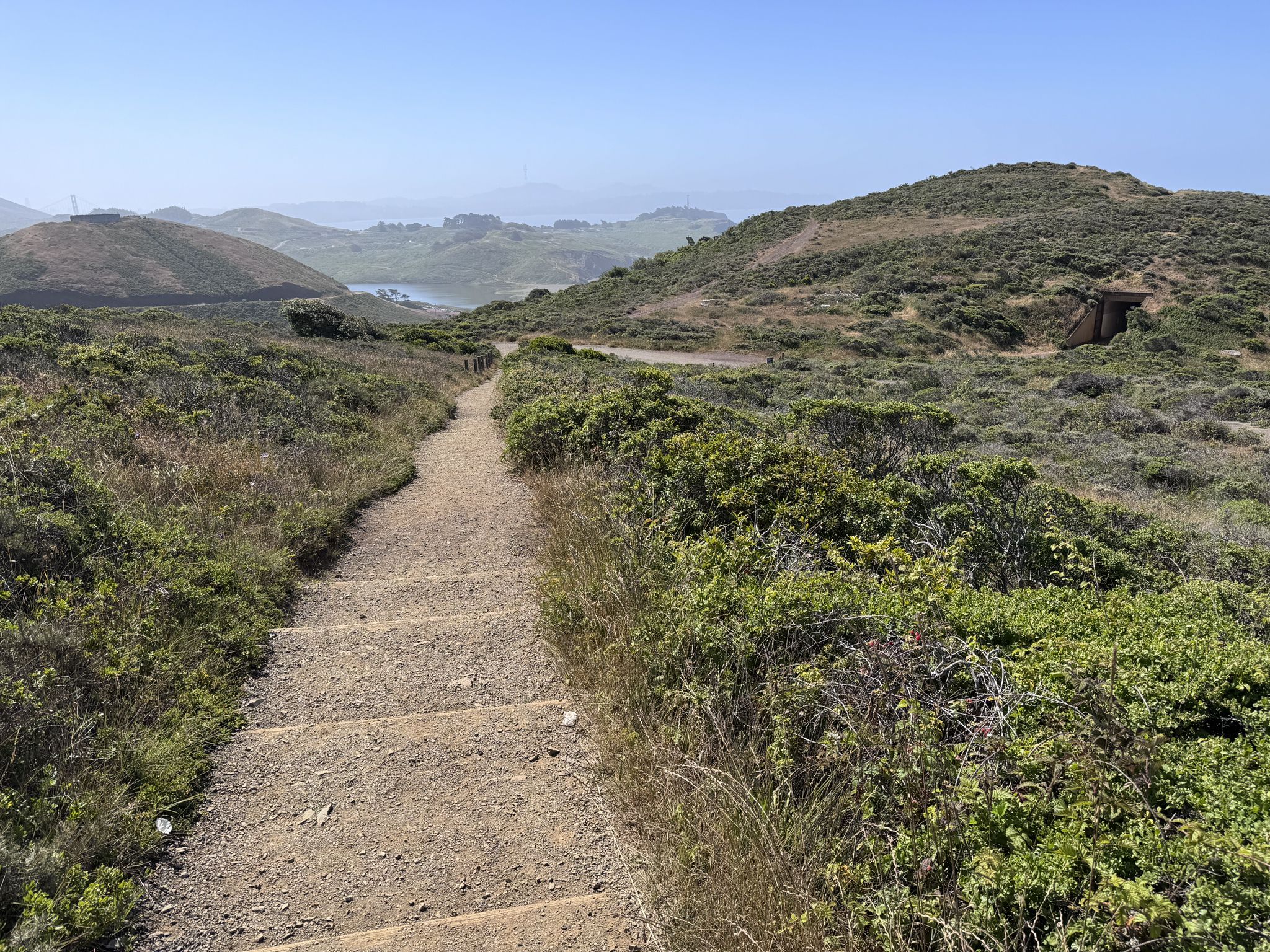 Dirt path with steps winding through green and dry rolling hills. - Coastal, Wolf Ridge, and Miwok Trails Loop