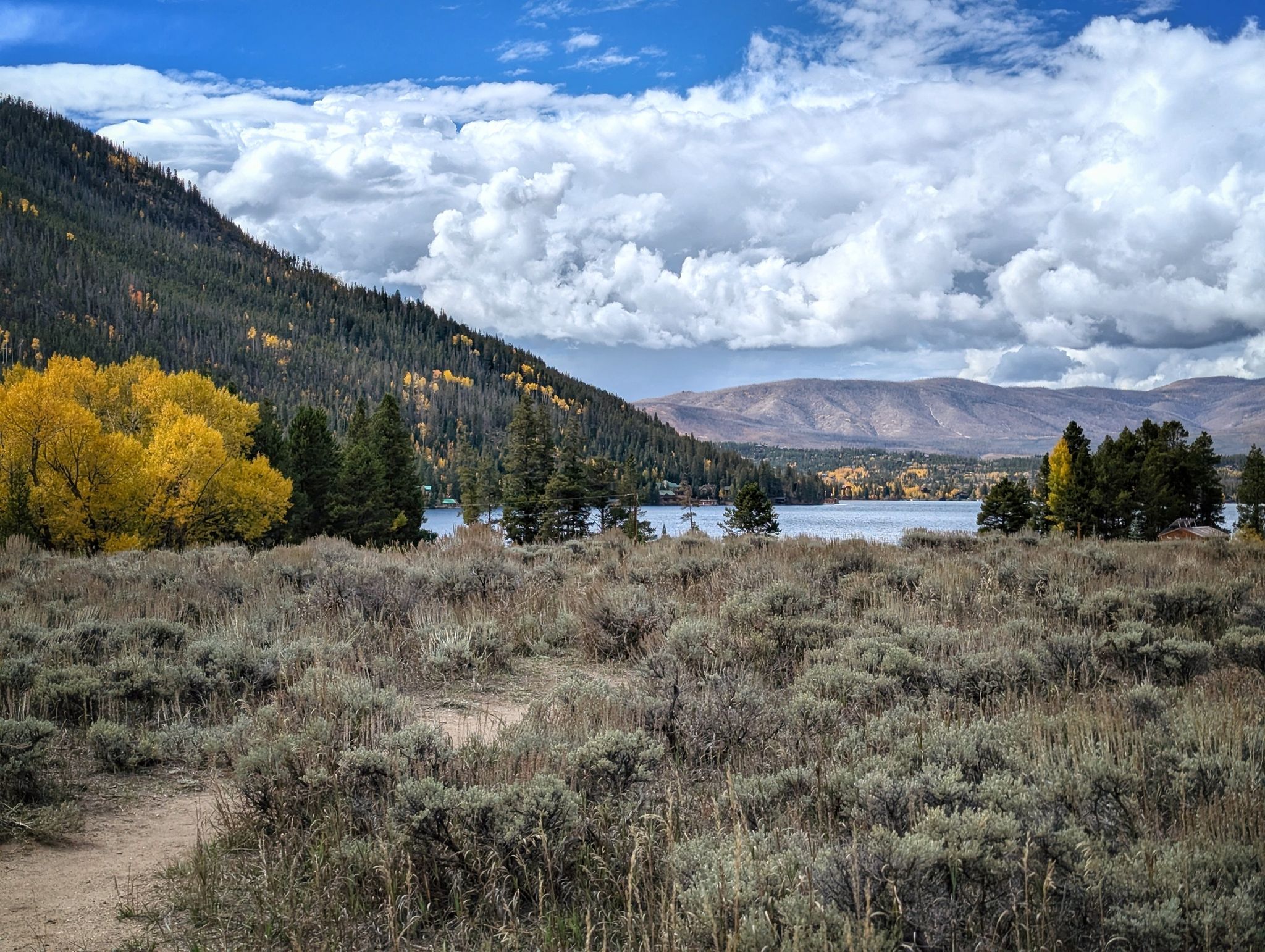 Sagebrush field with a lake, yellow trees, and mountains under cloudy sky. - Adams Falls Trail