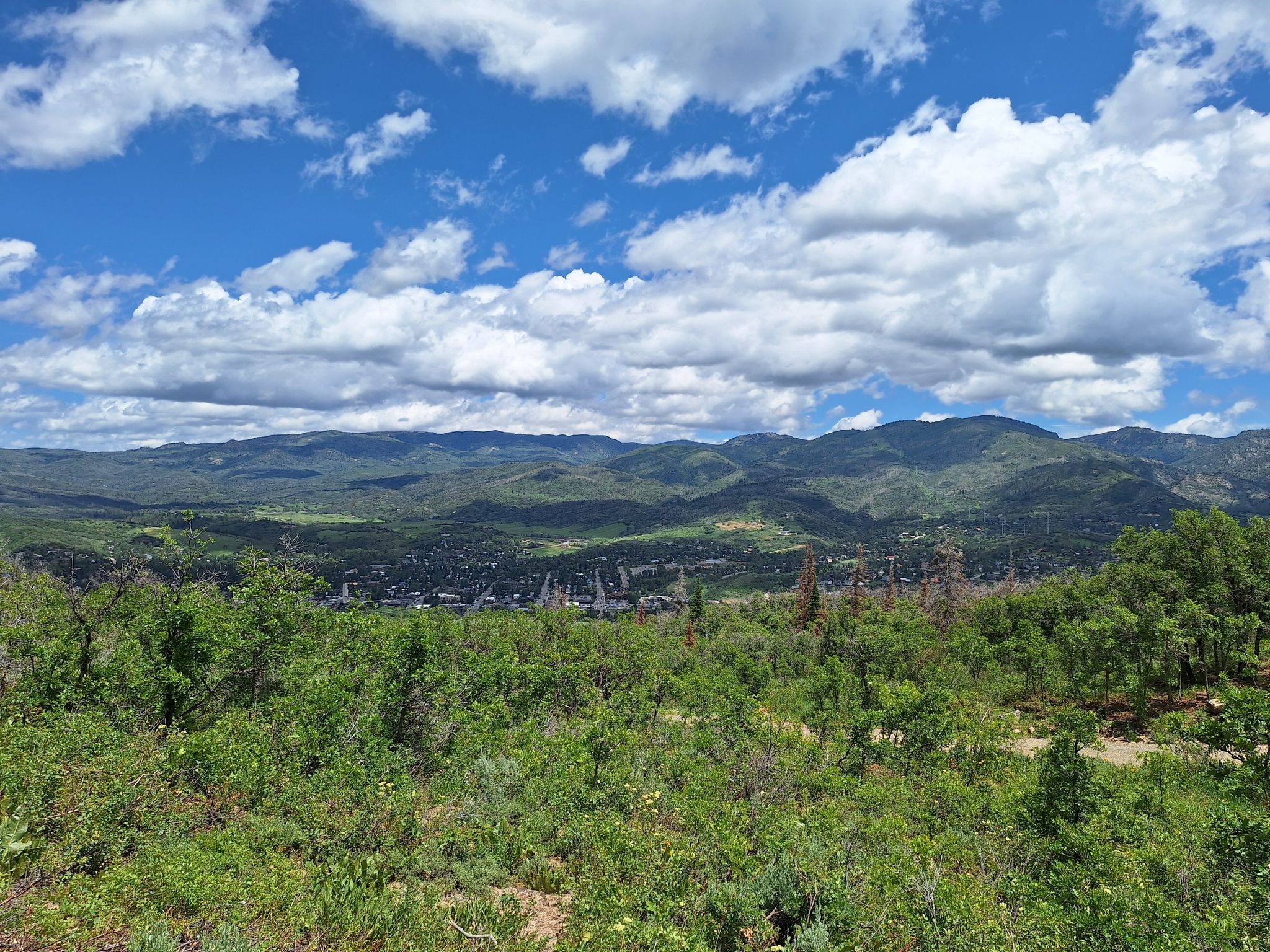 Panoramic view of green mountains and a valley under a cloudy blue sky. - NPR Trail loop from Steamboat Springs