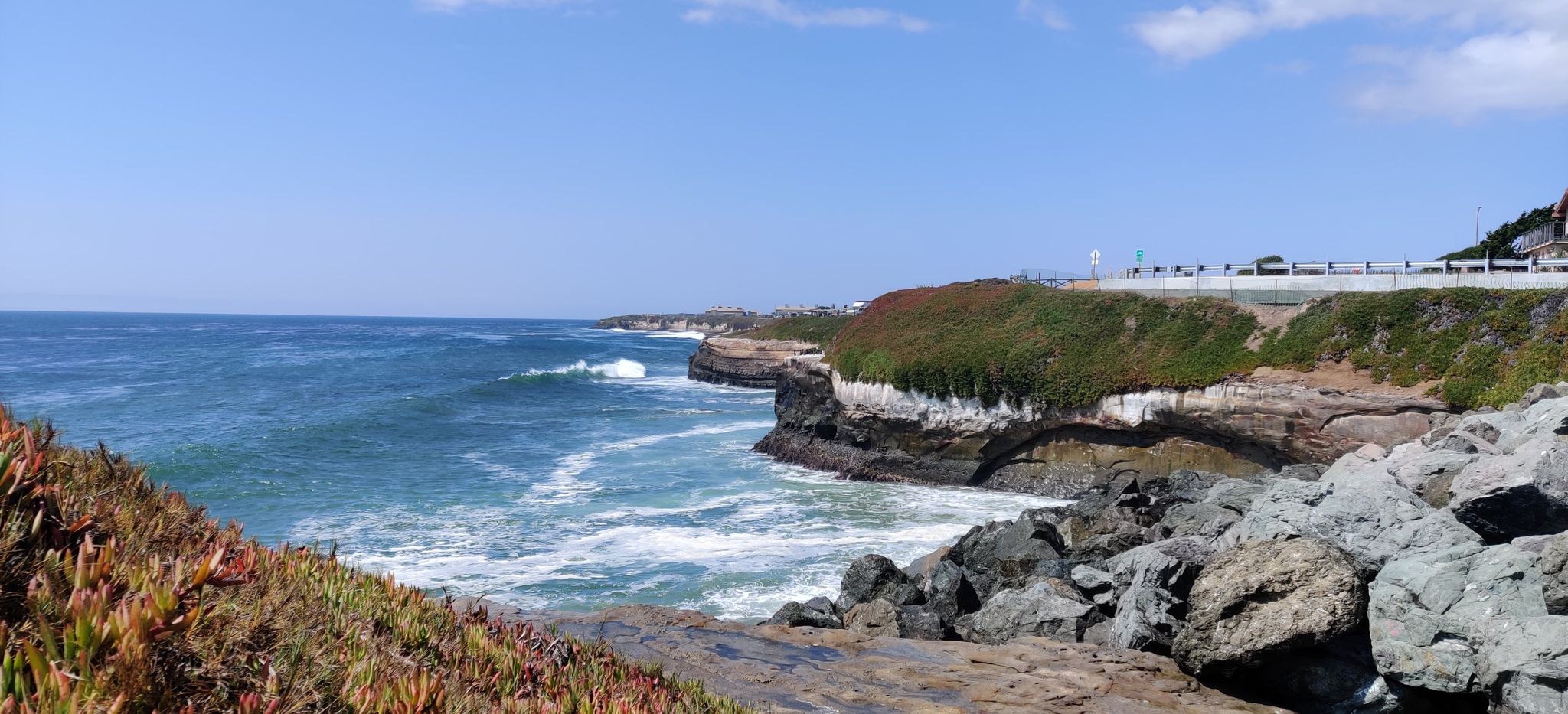 Bright daytime view of a rocky coastline with crashing waves and cliffs. - Natural Bridges State Beach loop from Natural Bridges State Beach